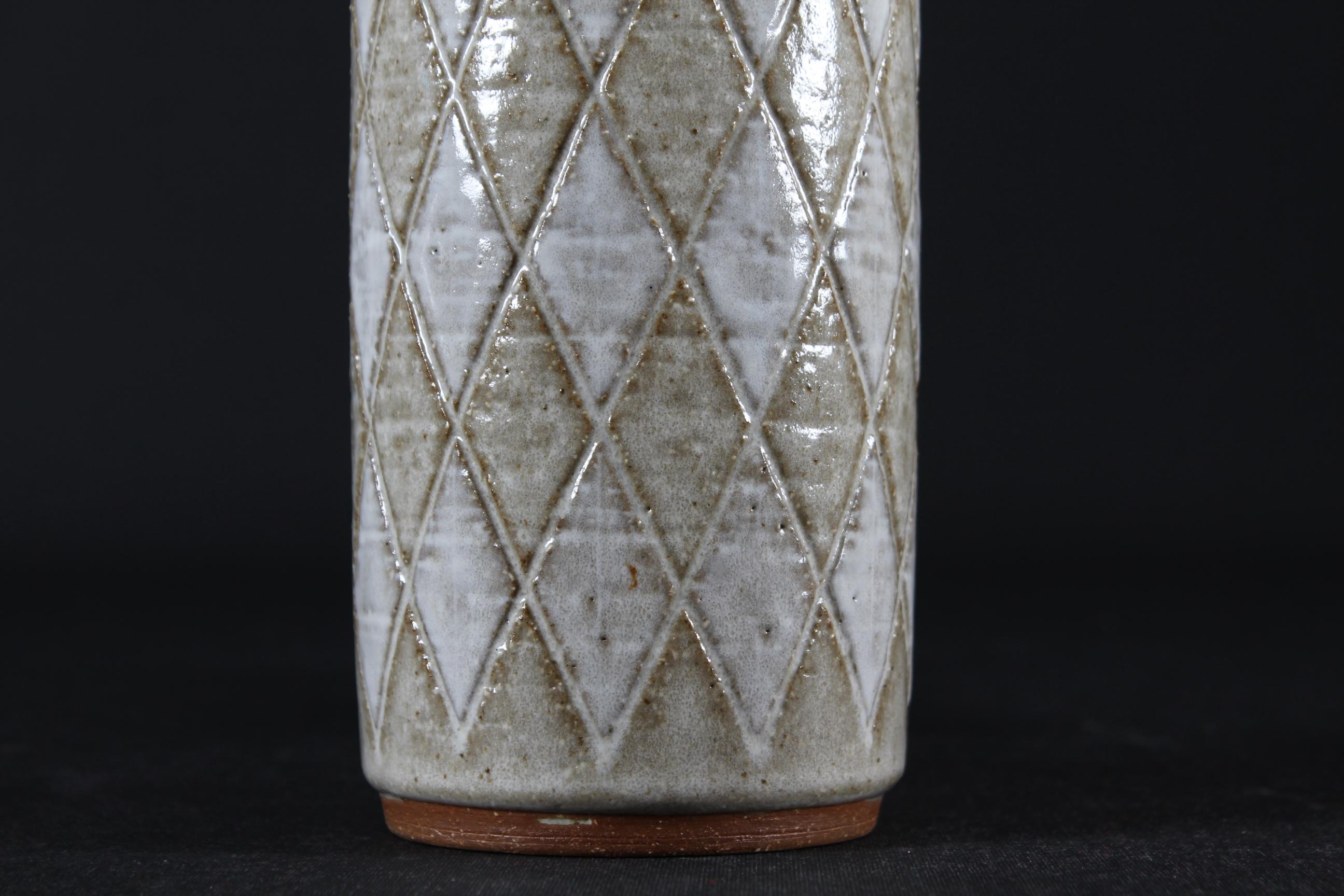 Per Linnemann-Schmidt Slender mid-century table lamp made by Danish Palshus Ceramic workshop in the 1960s.
It is made of chamotte clay which gives a rough and vivid surface. The glaze is white and beige in Harlequin checkered pattern.

Included