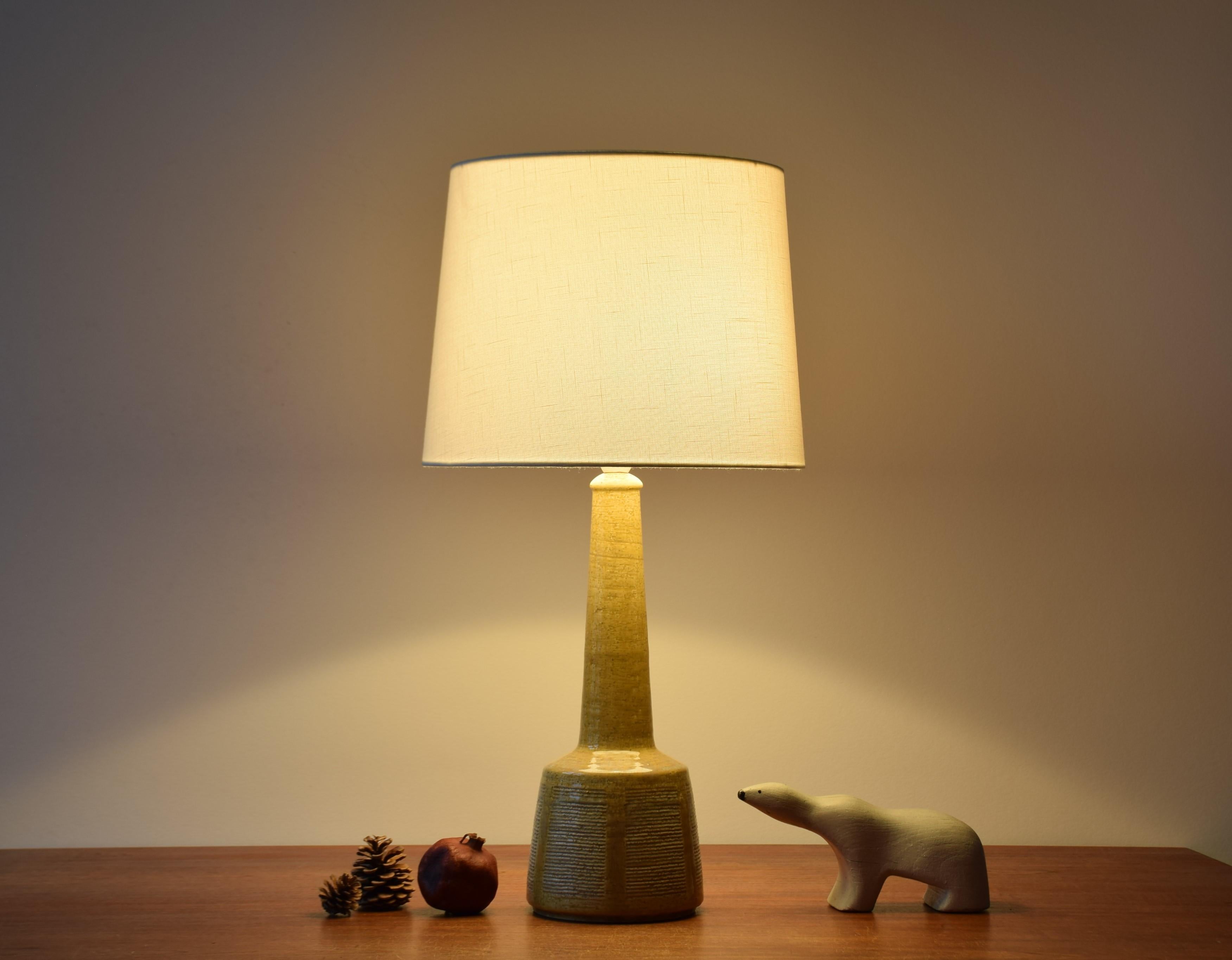 Tall Mid-Century Modern table lamp from Danish ceramic workshop Palshus.
The lamp was designed by Per Linnemann-Schmidt and manufactured circa 1960s.
It is made with chamotte clay which gives a rough and vivid surface. The glaze is yellow with a
