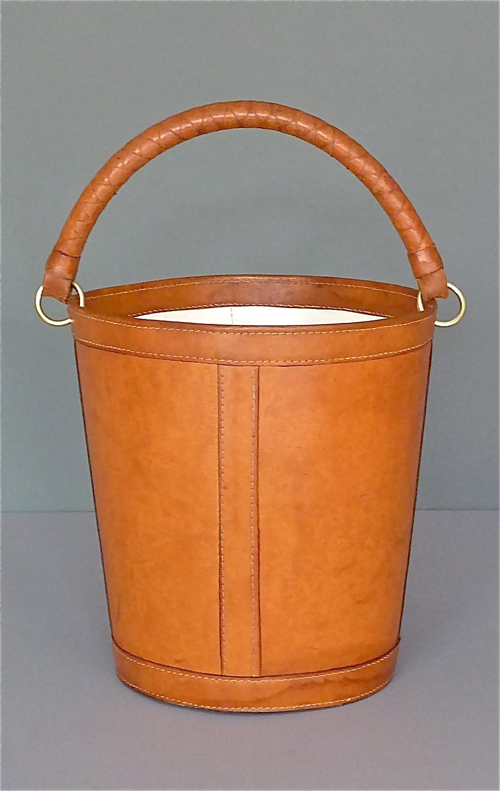 Beautiful midcentury patinated leather brass paper basket / office waste bin made in the 1950s-1960s by Illums Bolighus, Copenhagen, Denmark. The naturally aged basket is made of hand-stitched brown thick leather with an off-white plastic inlay and