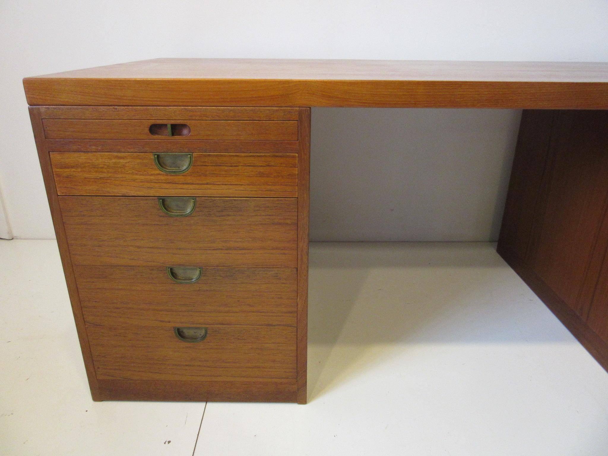A very well crafted teak wood pedestal desk with pull out writing surfaces to each side, five drawers with one file sized drawer. Great brass inset pulls and the desk comes apart in three pieces the top and the two-drawer sections for easy moving
