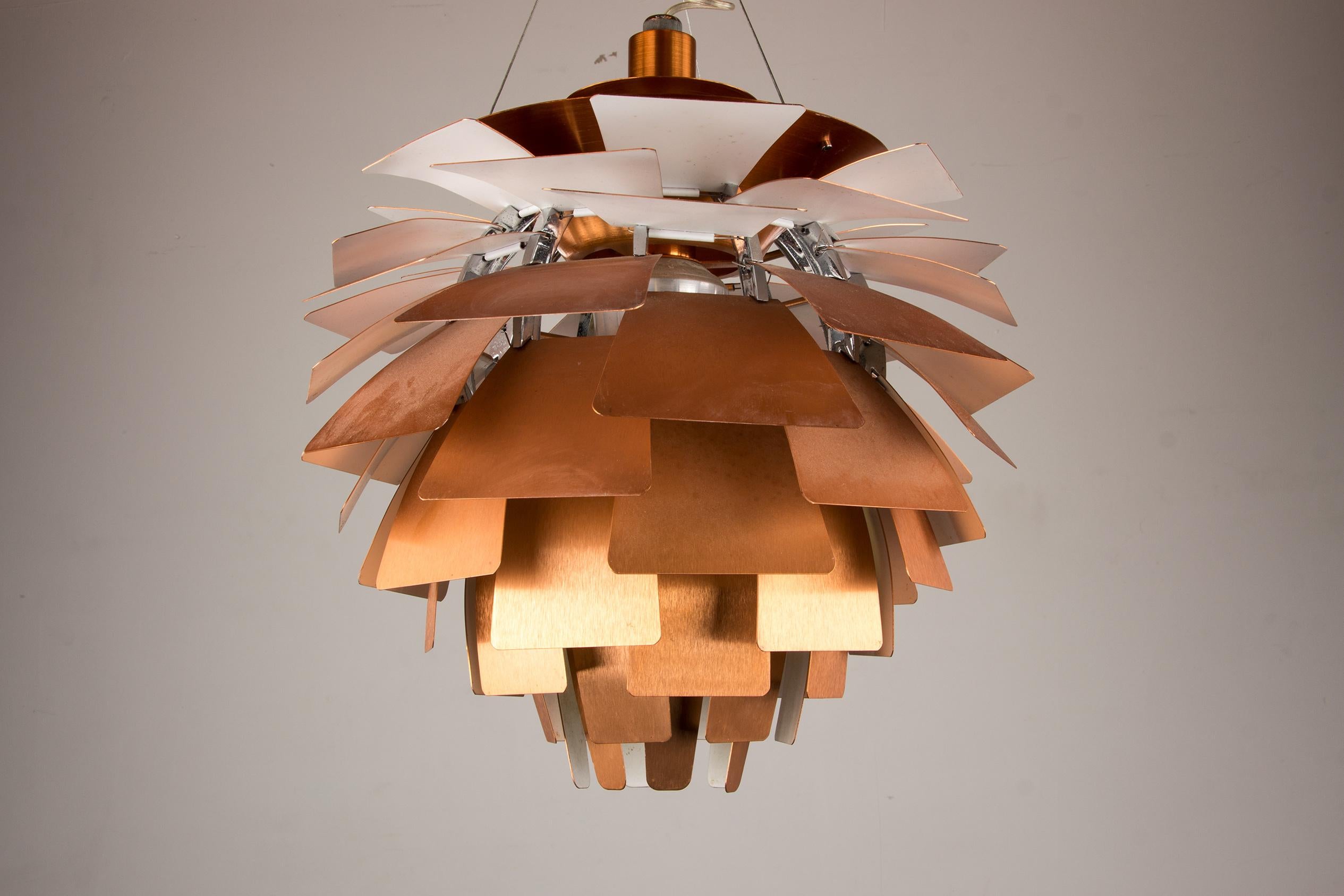 conic Scandinavian Pendant Lamp, the PH Artichoke was created in 1958 and is still produced.    The structure consists of twelve steel arches on which seventy-two copper plates are placed in twelve circular rows, with six blades in each row. Each