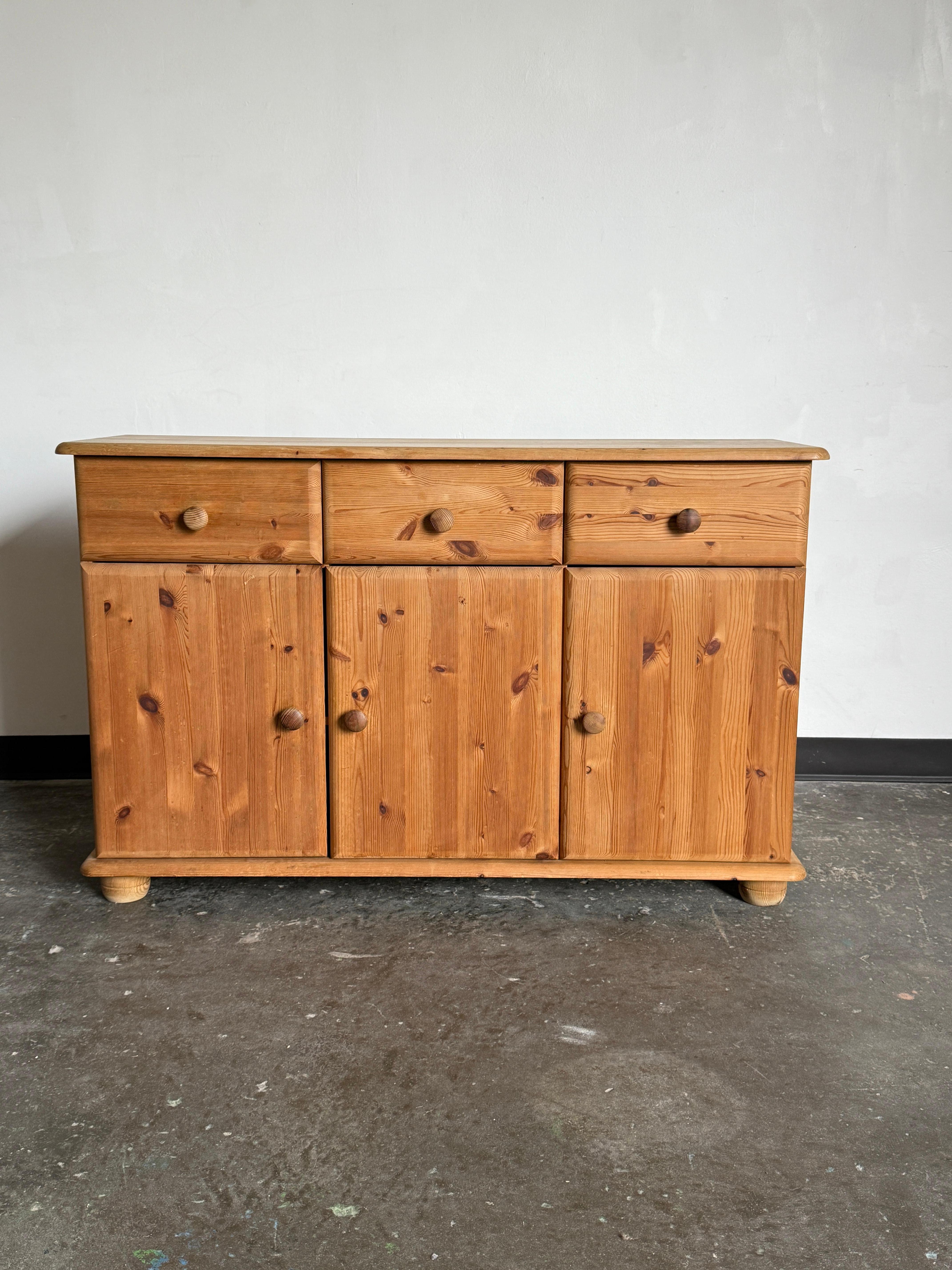 Danish modern pine side board in excellent vintage condition with age-consistent wear. Features three pullout drawers with three doors/two lower compartments with shelves. 