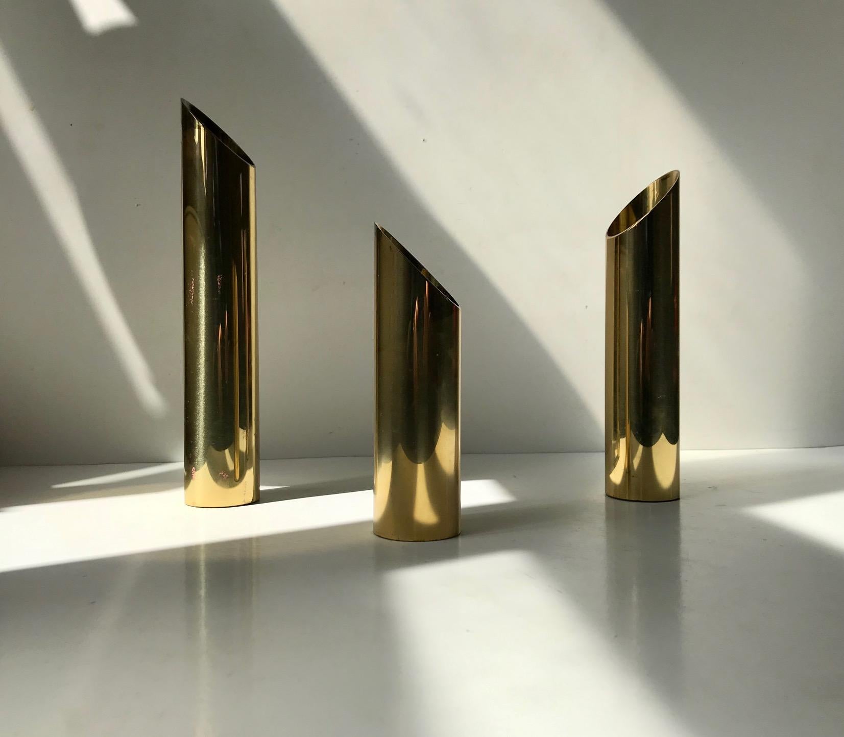 A set of 3 Danish modern tea light candleholders. Made from pipe shaped solid brass in 3 diffrent heights. The tea lights are 'resting' in such a way that only the flame is visible. Alternatively they can also be installed with church/bloc candles.