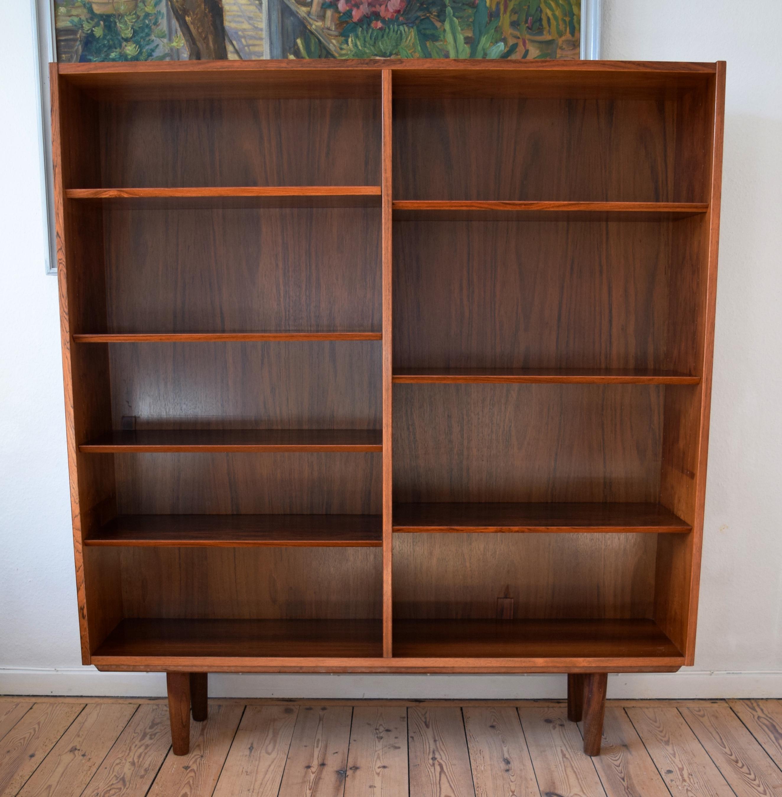 Rosewood bookshelf manufactured in Denmark by Poul Hundevad. Features adjustable shelves and sits on a frame base with teak legs. Very well made bookshelf from one of Denmark's foremost cabinet makers. Stunning rosewood grain throughout. Some