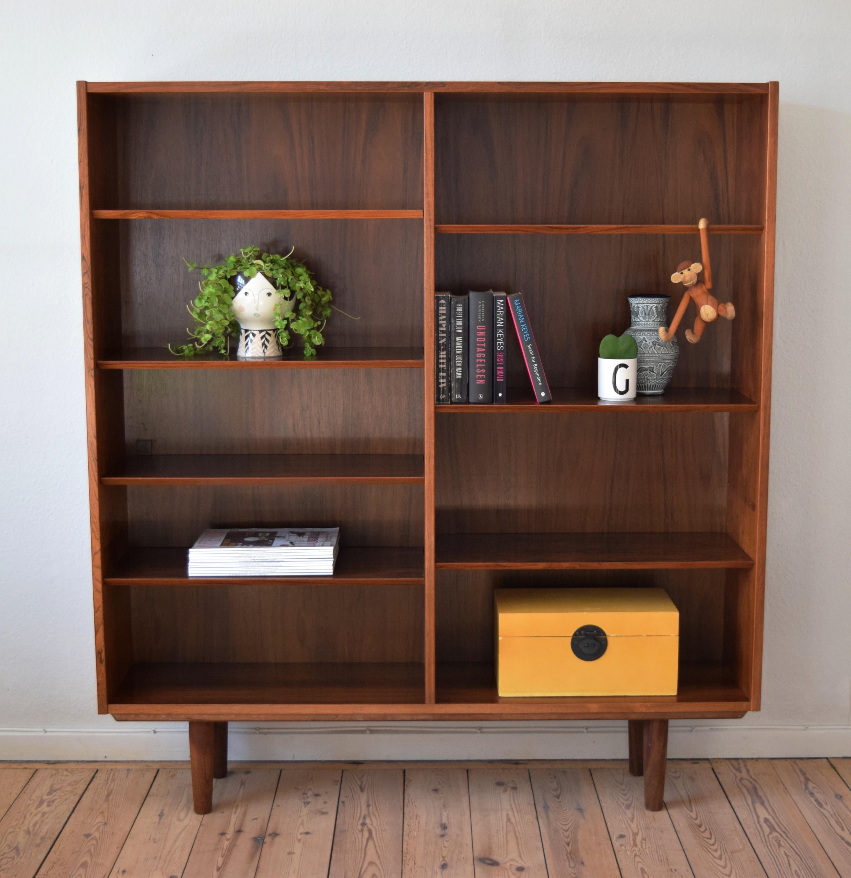 Rosewood bookshelf manufactured in Denmark by Poul Hundevad. Features adjustable shelves and sits on a frame base with teak legs. Very well made bookshelf from one of Denmark's foremost cabinet makers. Stunning rosewood grain throughout. Some