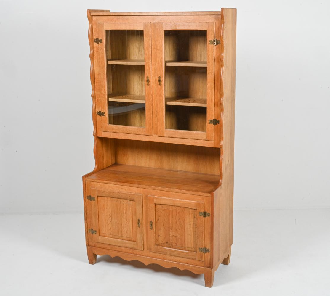 At once rustic and Modern, this beautiful tall cabinet by Henning Kjærnulf features a step-back silhouette, with traditional raised panel molding at the lower cabinet doors and a glazed upper cabinet that's perfect for protecting and displaying your