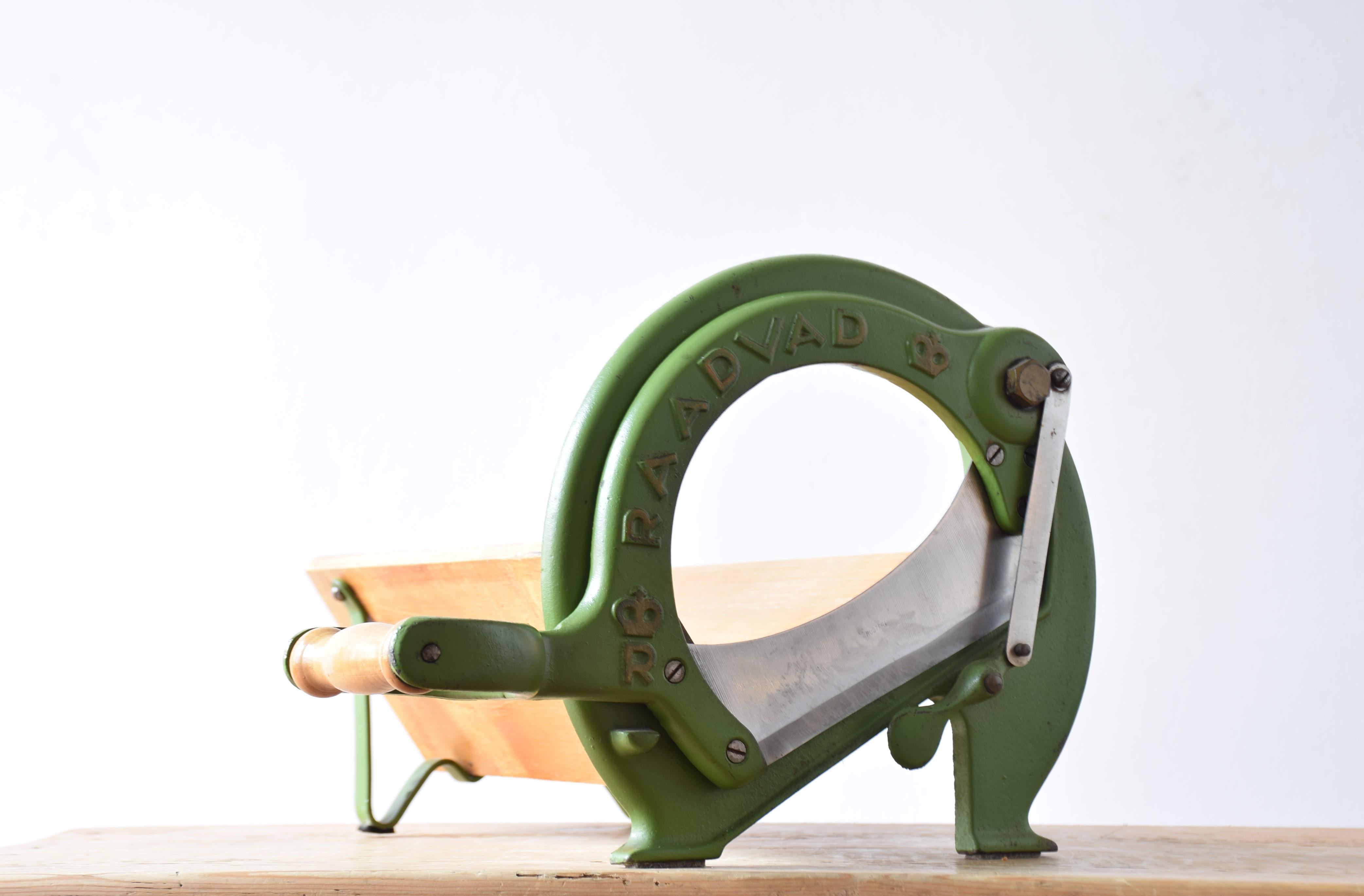 Questa iconica affettatrice danese è stata prodotta da Raadvad in Danimarca tra gli anni '40 e '60 circa e progettata negli anni '30. Viene fornito con la lacca verde originale e presenta ancora parte della vernice dorata originale su lettere e