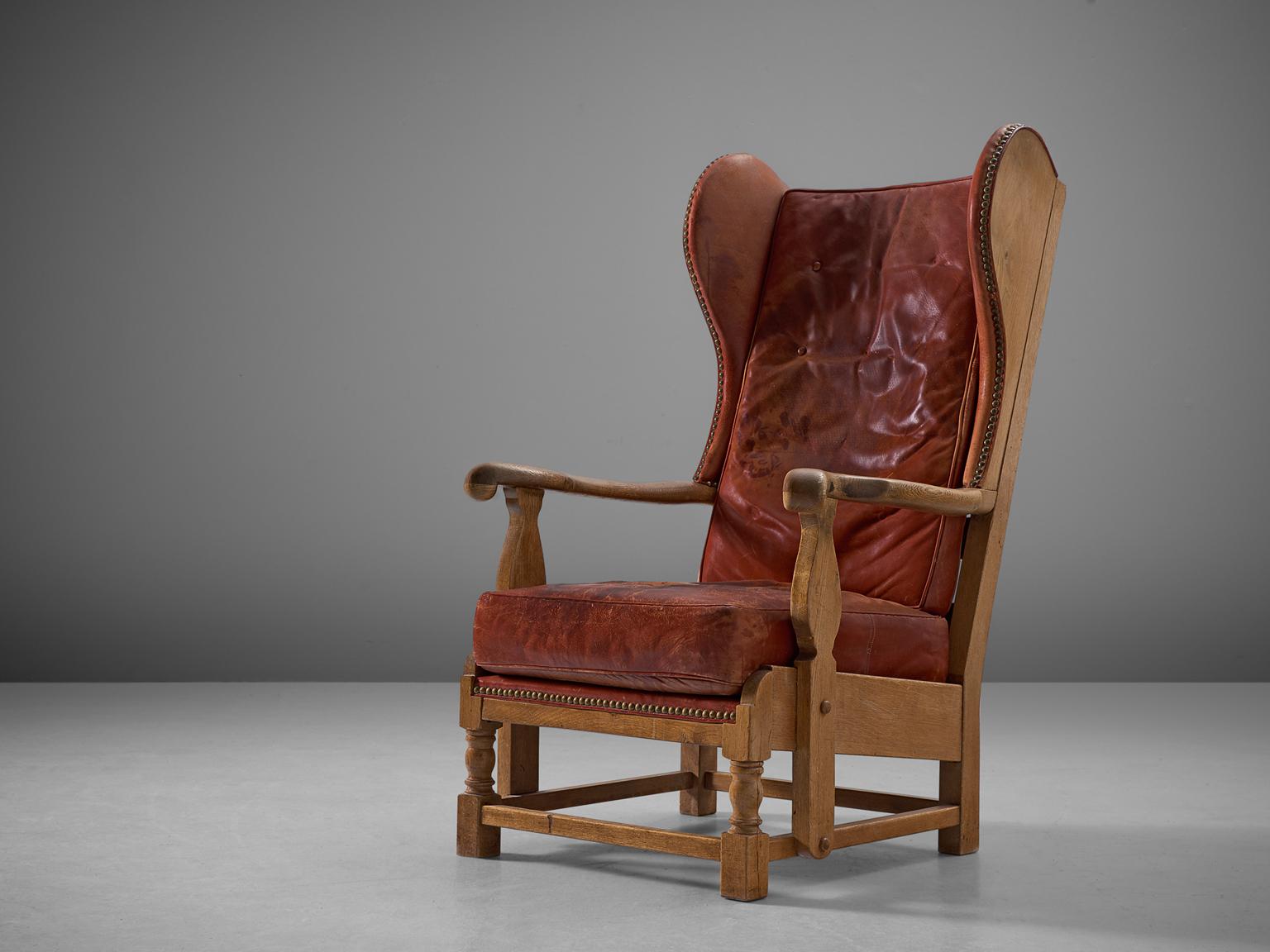 Lounge chair, red leather and oak, Denmark, 1930s.

This very rare early Danish lounge chair has the traits of a wingback chair whilst at the same time breathing the atmosphere of a gone century. This chair is easily pictured in a country house. At