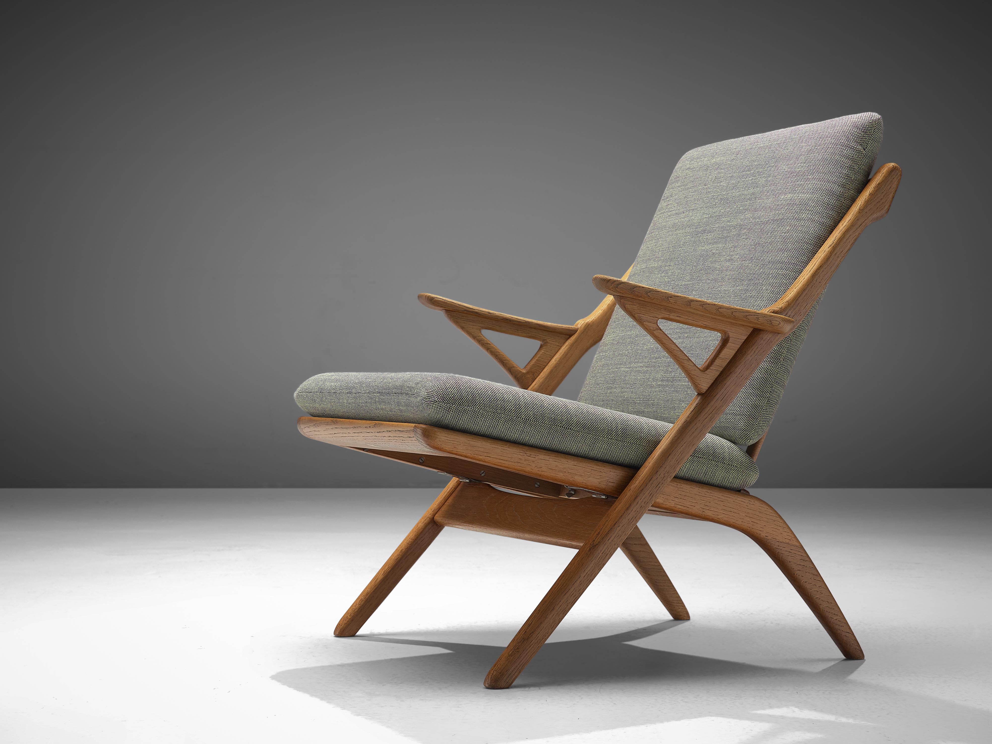 Armchair, in oak and fabric, Denmark 1960s. 

Easy chair in solid oak with sculptural elements. What looks like a simple folding chair is in fact a wonderful armchair. The frame of solid oak has beautiful elements, such as the slatted back and