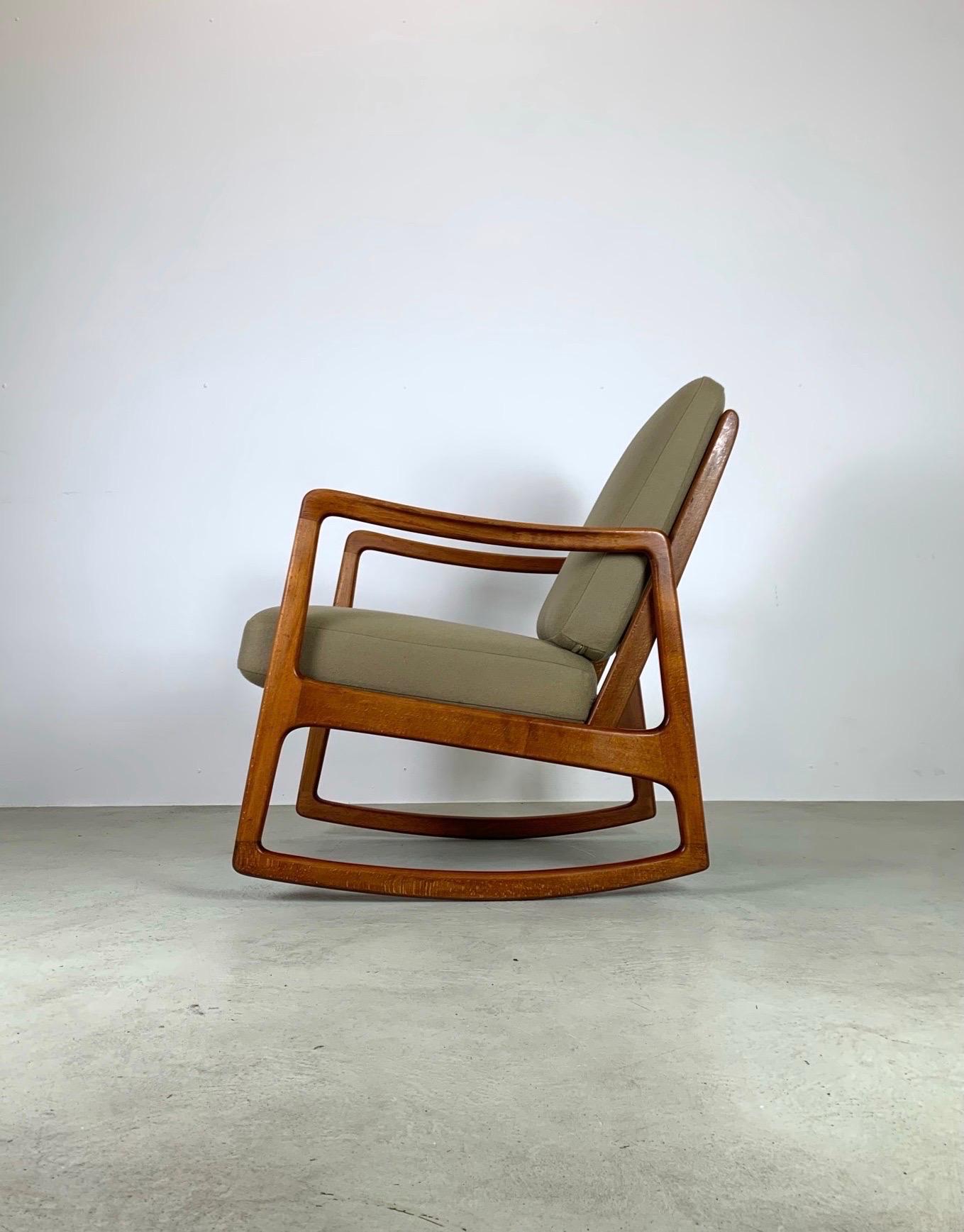 Rare mid-century rocking chair designed by Danish Professor Ole Wanscher. Made in Denmark by France & Søn during the 1950s. It maintains the manufacturer’s mark and features a sturdy teak wooden frame with a slated open back and angled legs for an