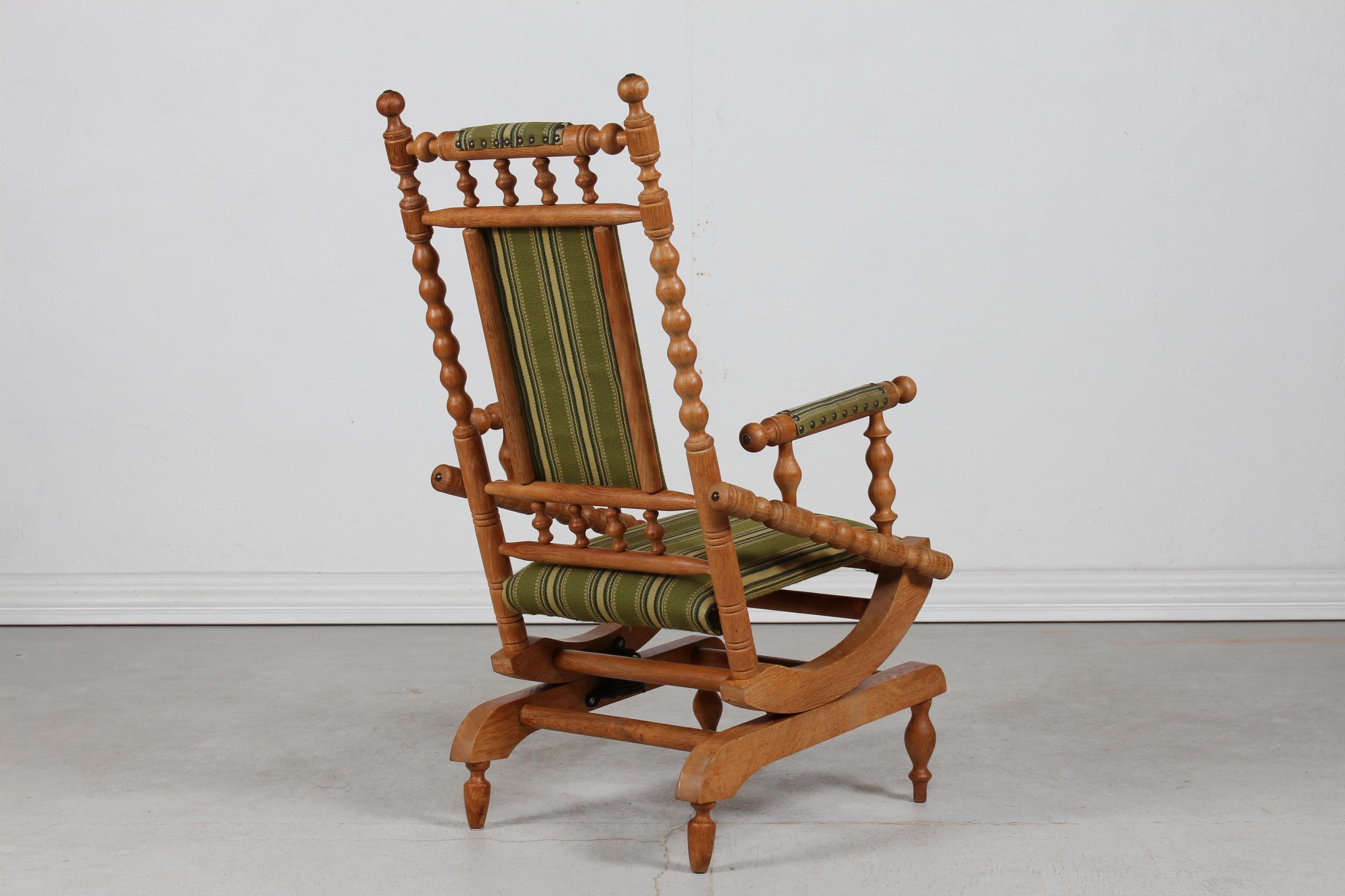 Danish vintage rocking chair in the style of designer Henning Kjærnulf. 
The frame and armrests are made of turned solid oak upholstered with the original striped wool with brass nails. 

Nice original vintage condition with patina after gentle