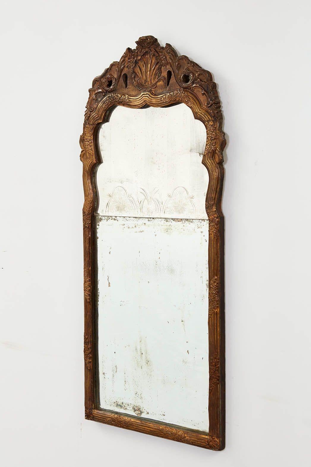 Fine 18th century Danish or Swedish rococo mirror having a shell decorated crest with foliate adorned ribbed frame, the original arched beveled plate with etched decoration, over well oxidized beveled lower plate.