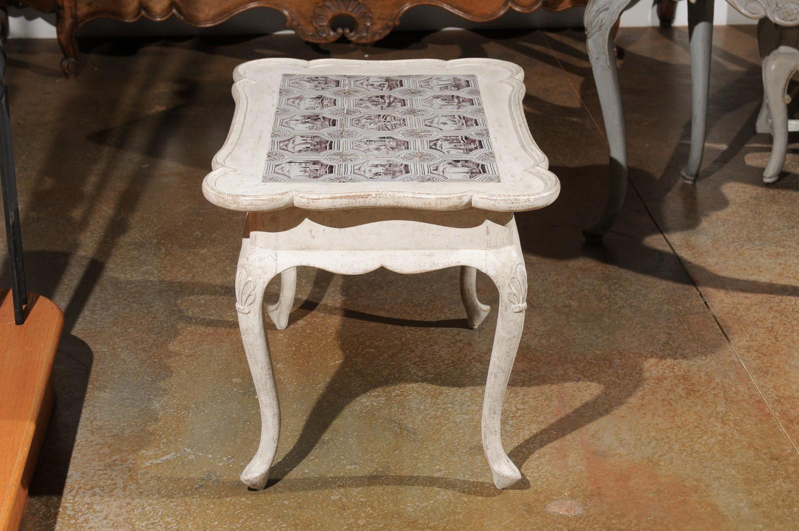 A Danish painted wood Rococo style table from the 20th century, with tiles, cabriole legs and carved apron. Created in Denmark during the 20th century, this Rococo style table features an eye-catching top with serpentine lines and tile decor,
