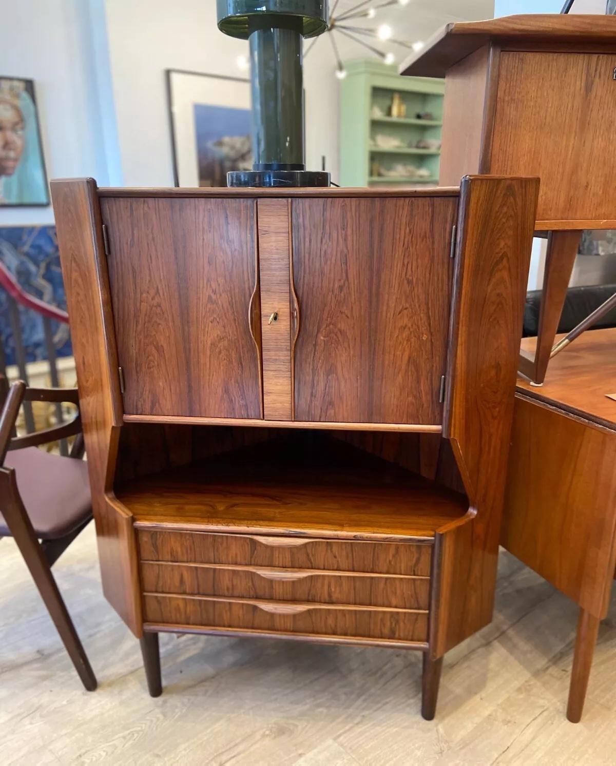 Eleva il tuo intrattenimento a casa con questo squisito bar danese ad angolo in palissandro vintage degli anni '60 di Omann Jun. Progettato con un sofisticato armadio chiuso dotato di due spaziosi ripiani, offre un ampio spazio per i tuoi bicchieri