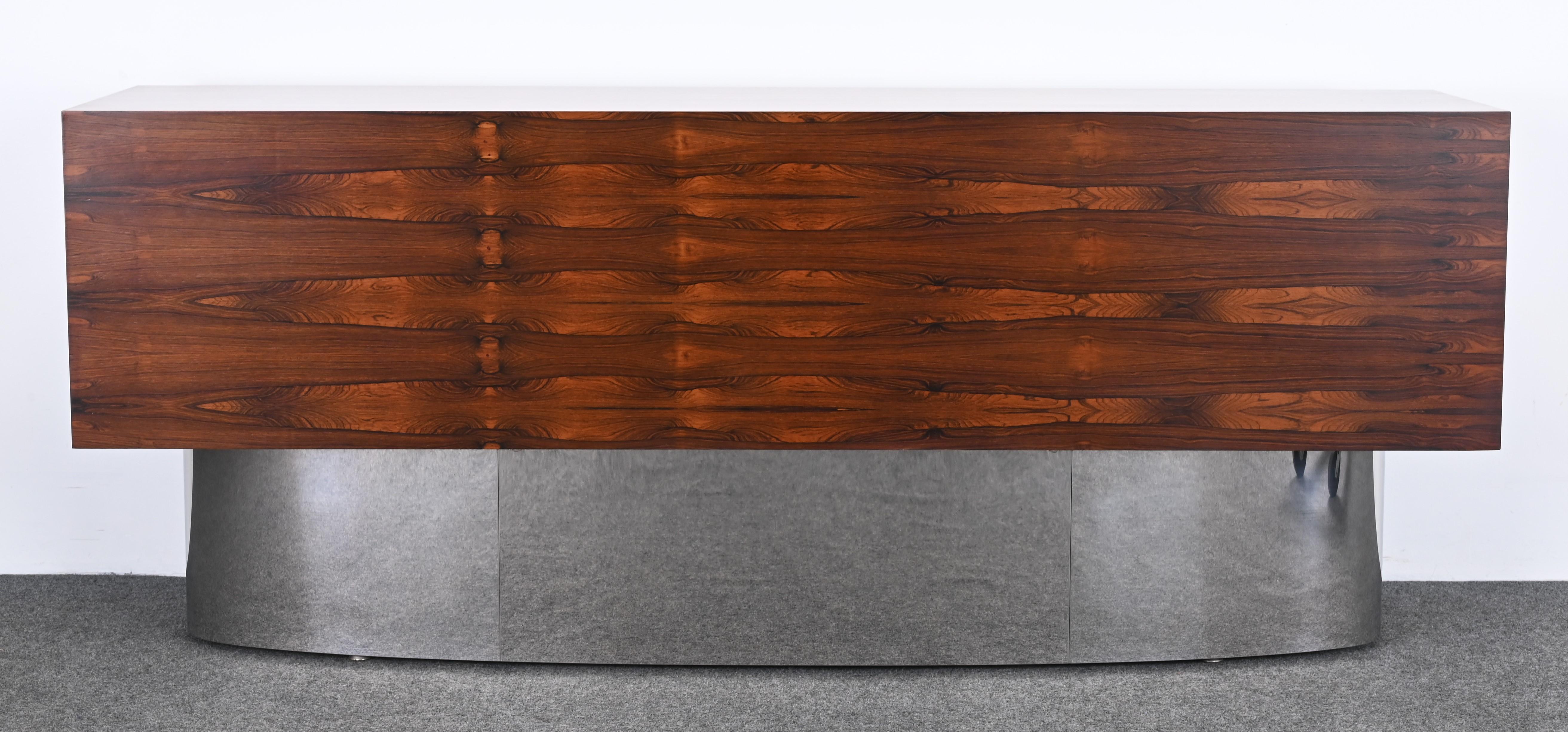 A gorgeous rosewood credenza or sideboard with a chrome base, made in Denmark, circa 1960s. This beautiful piece has amazing rosewood graining. The cabinet has four drawers and two sliding doors for ample storage. This piece would look great in any