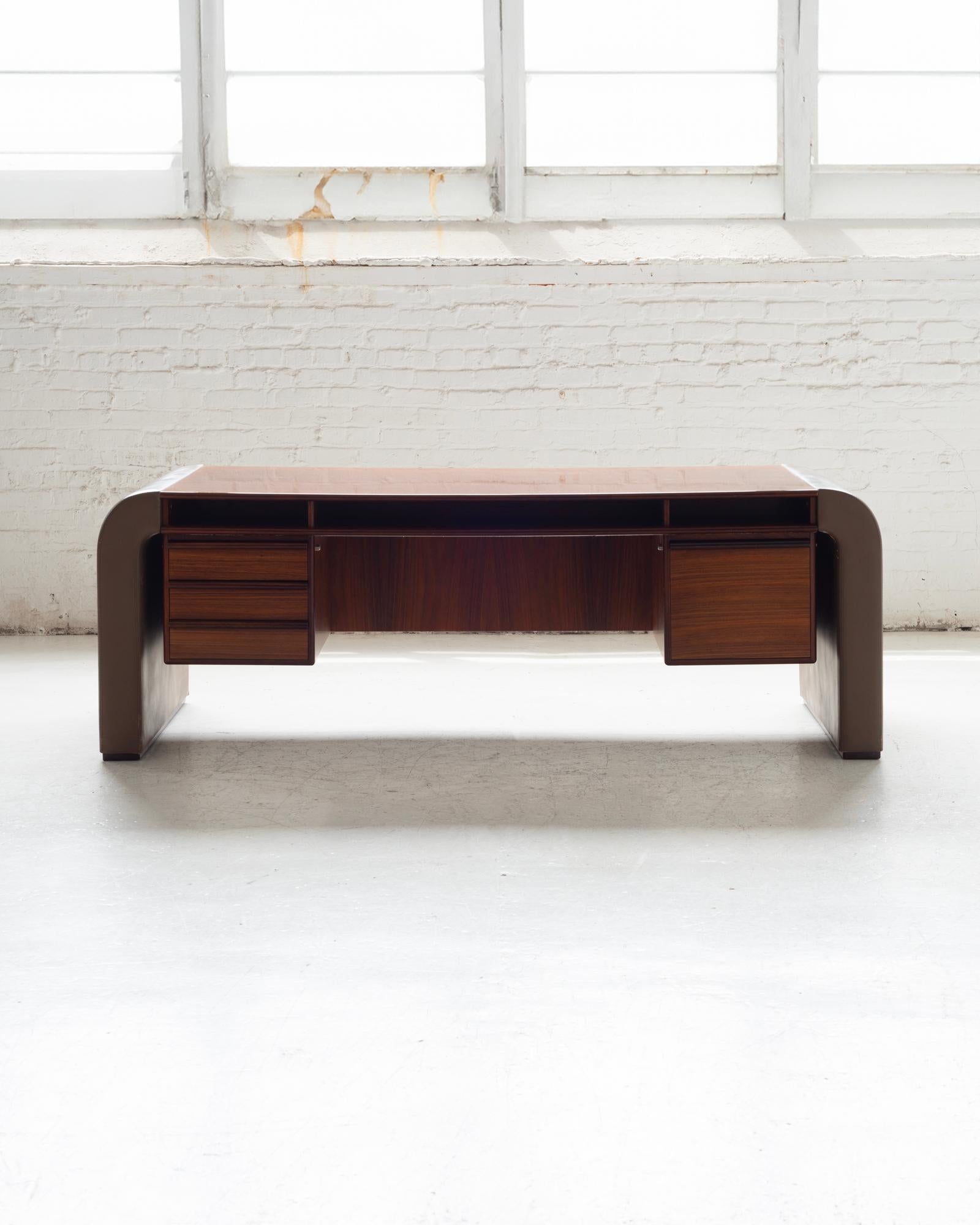 A stunning vintage Danish rosewood desk by Berg, perfect for any discerning collector or interior design enthusiast. This exquisite piece features leather-wrapped waterfall legs, adding a touch of luxury and elegance. The desk is equipped with a