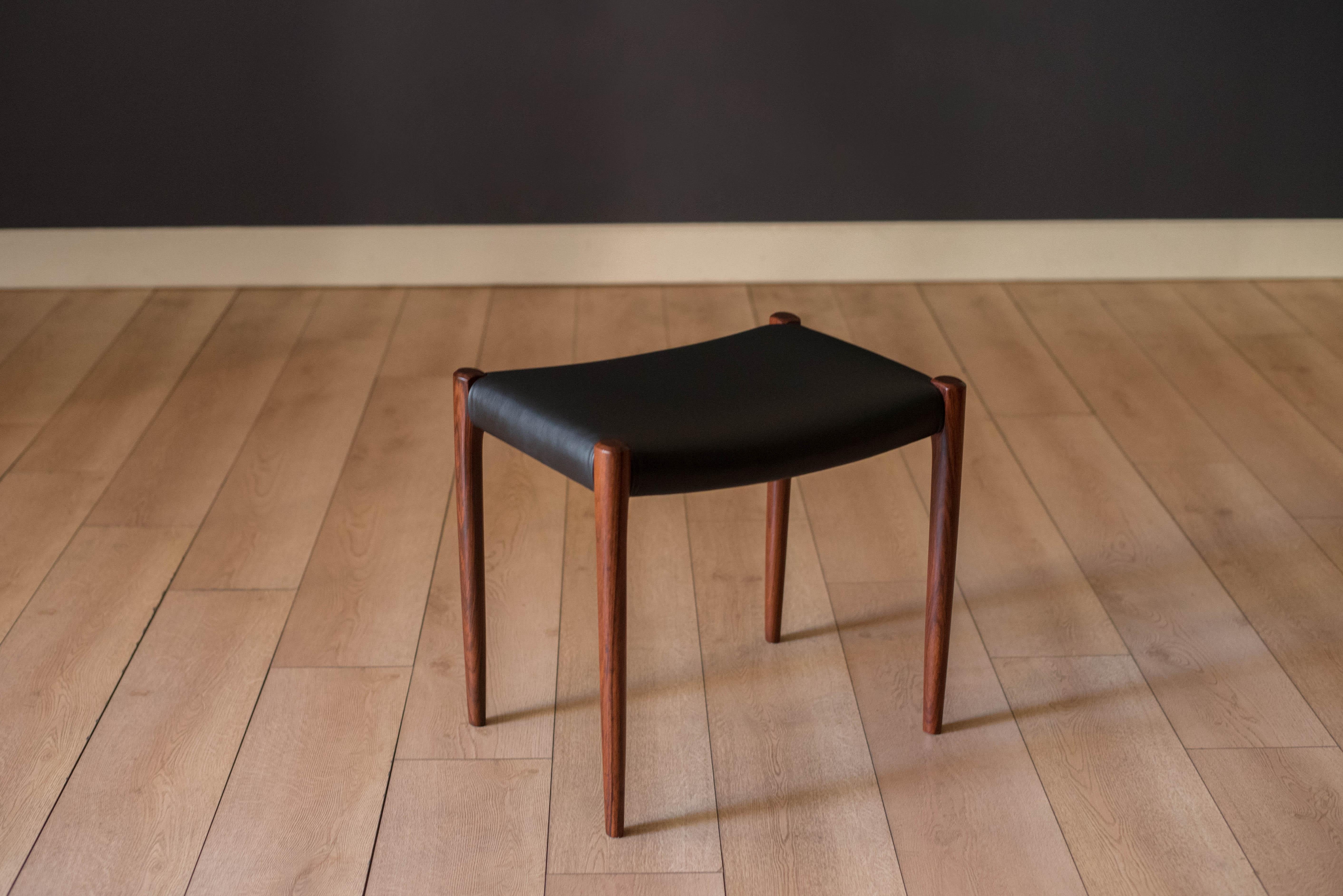 Mid Century Modern dining chair stool model 80A designed by Niels O. Moller for J.L. Mobelfabrik. This piece features a minimalistic design crafted with sculptural solid rosewood legs. It has been professionally reupholstered and wrapped in black