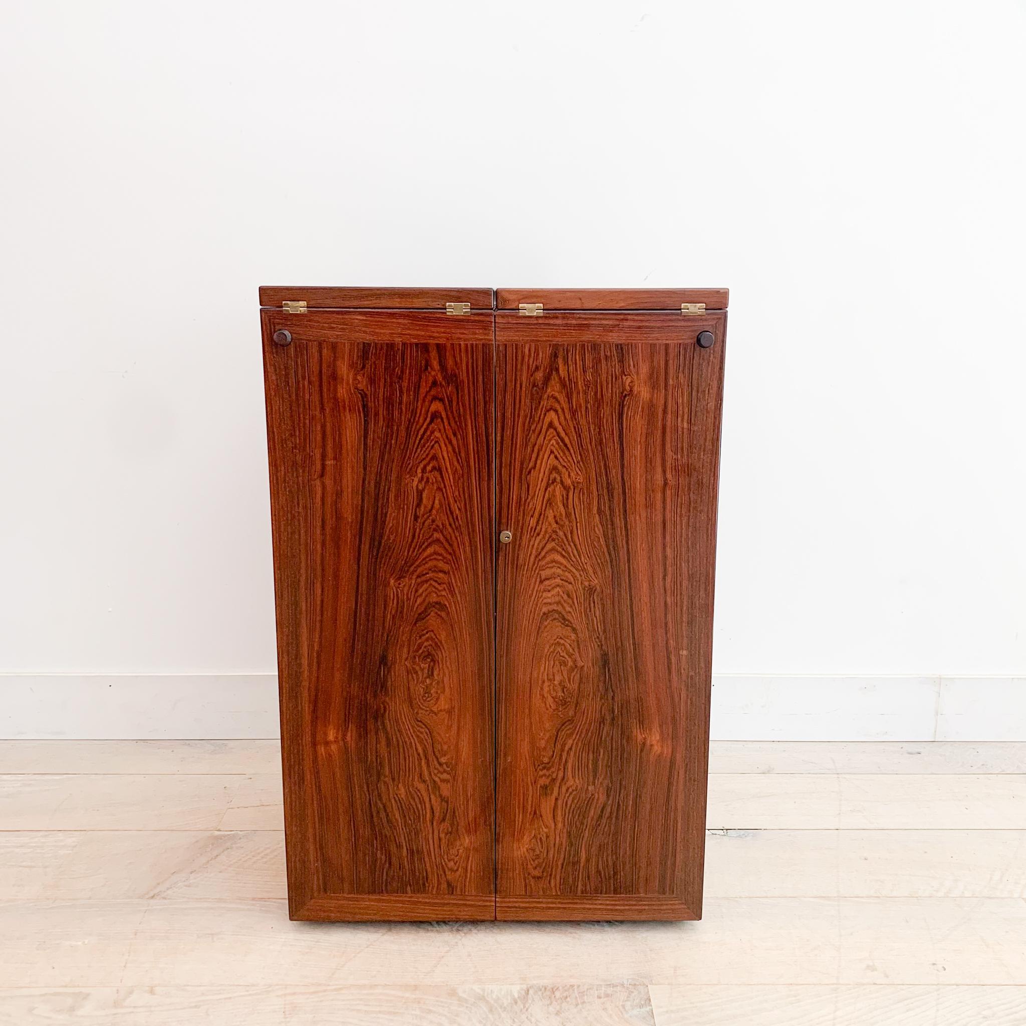 Add a touch of classic elegance to your space with this exceptional mid-century modern Danish rosewood bar cabinet, designed by the renowned Reno Wahl Iversen for Dyrlund. This piece is in great overall condition, with some light scuffing and