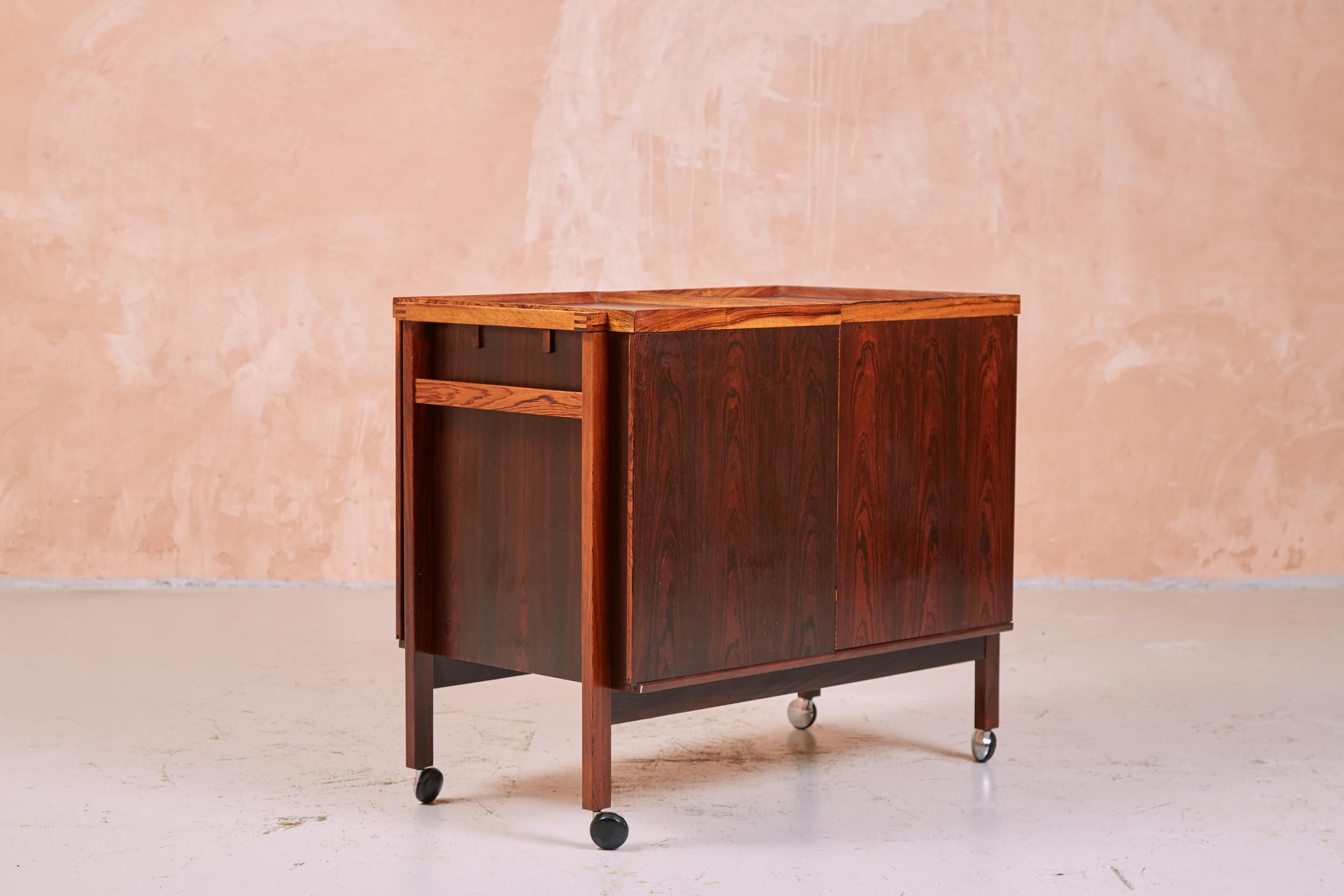 This gorgeous example of an iconic Danish designed bar cart has amazing rosewood grain which makes it a standout.
A piece of functional art furniture designed by Niels Erik and Glasdam Jensen for Vantinge Møbelindustri, dating from 1964. Opens with