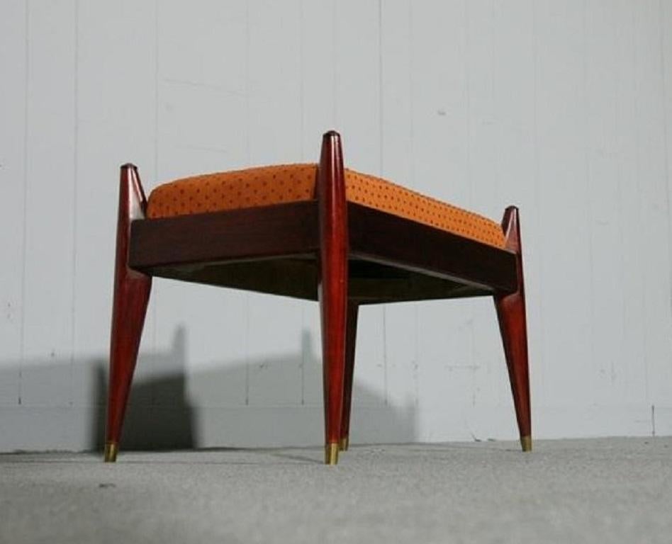 Banc en bois de rose danois. Le banc a un cadre en bois de rose avec un siège rembourré de coussins orange.