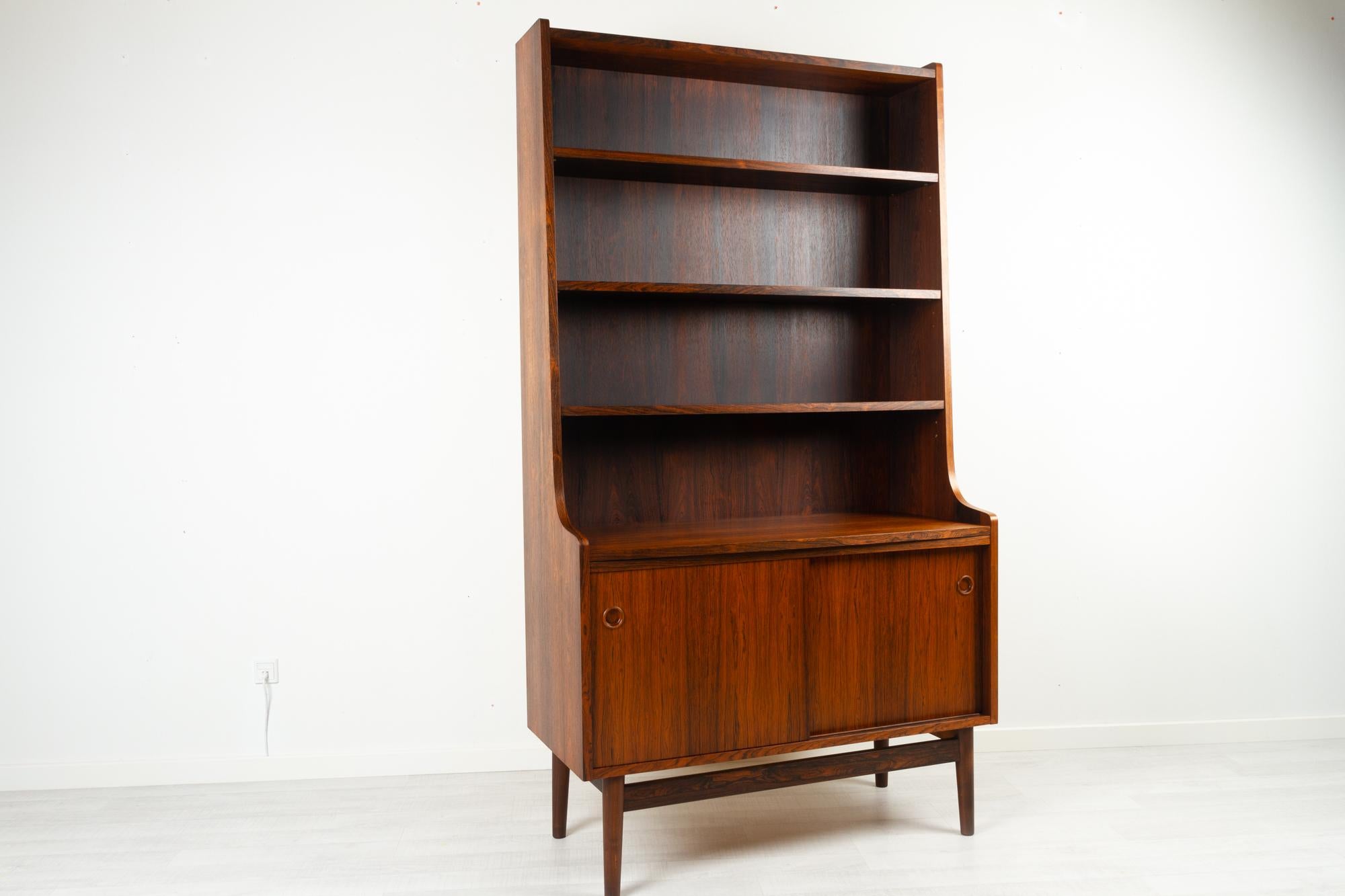 Danish rosewood bookcase by Johannes Sorth for Nexø Møbelfabrik, Bornholm, Denmark 1960s. 
Danish Mid-Century Modern bookcase in rosewood. Cabinet with double sliding doors and one height adjustable shelf. Top with three height adjustable