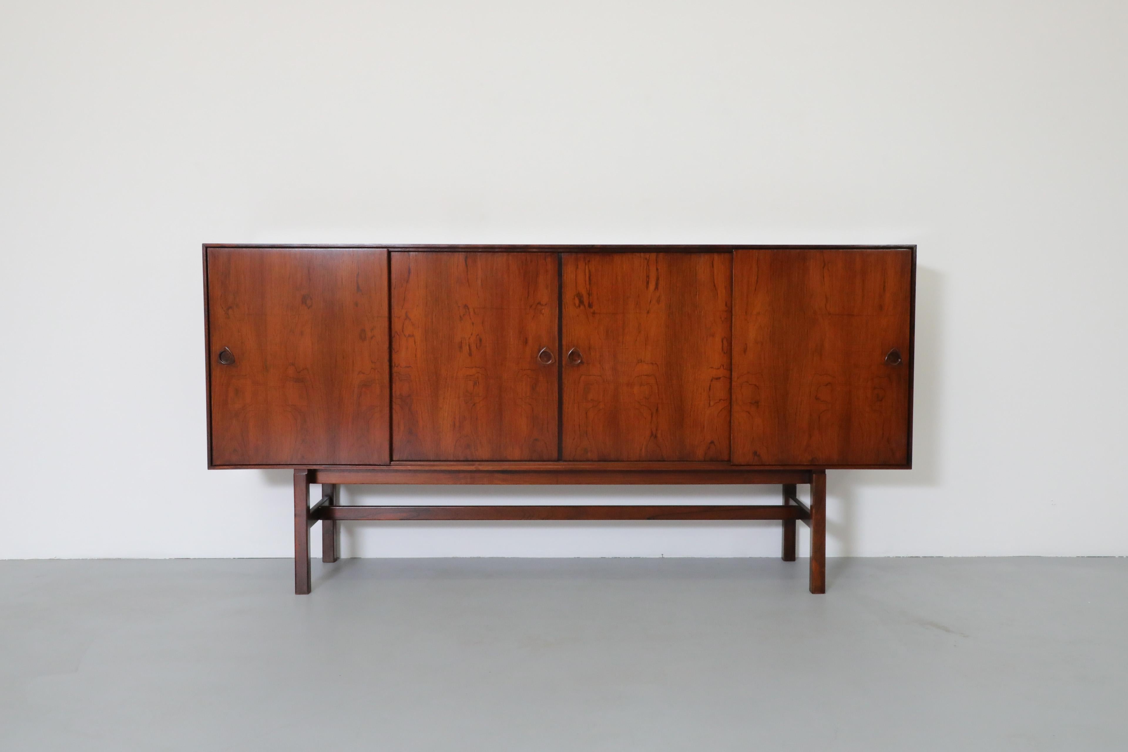 Beautiful Mid-Century Modern Danish rosewood highboard designed by Erik Brouer for Brouer Møbelfabrik. The highboard has shelving on both sides as well as bar with a mirror and light in the bar section. The light has an internal switch and turns on
