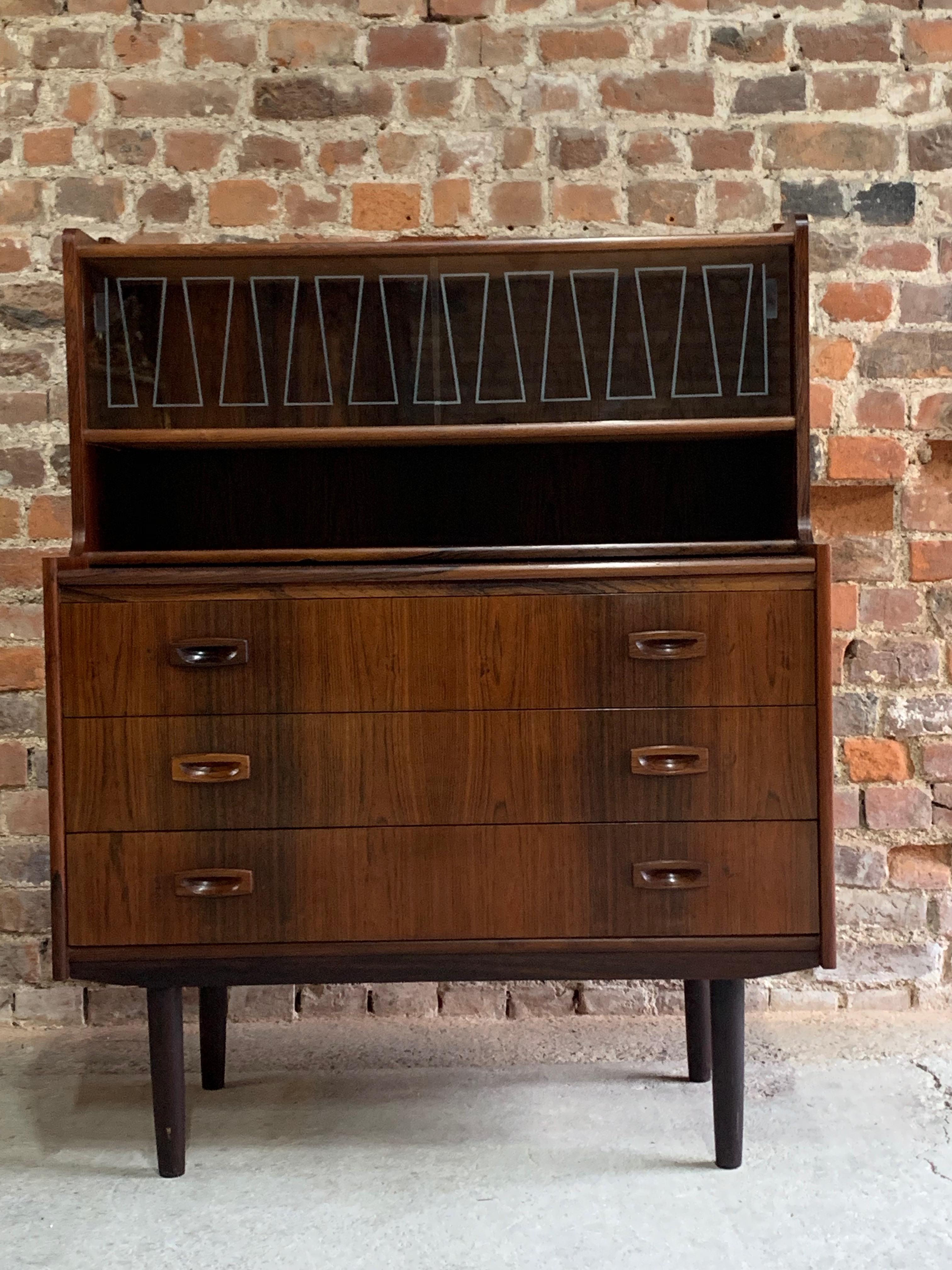 A beautiful Danish rosewood bureau circa 1960s, the raised back with two sliding lithographed glass doors over a sliding writing surface and three drawers, raised on four tapered legs, this piece comes with a current cities certificate but will
