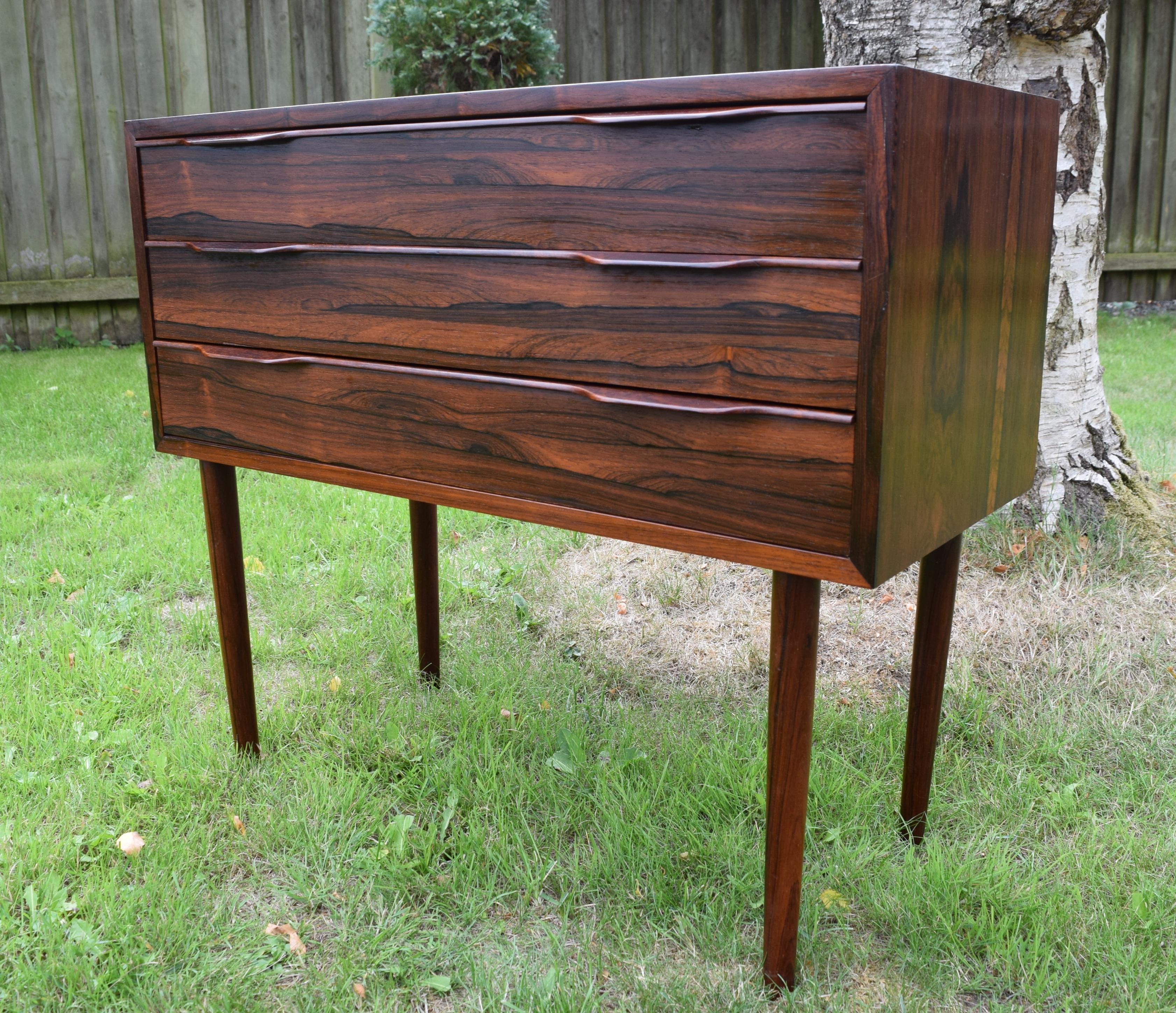 Small chest of drawers designed in Denmark in the 1960s. Features three drawers with solid rosewood drawer pulls. Stunning Brazilian rosewood grain runs throughout this piece. The legs are turned from solid rosewood. Apart from a few small marks