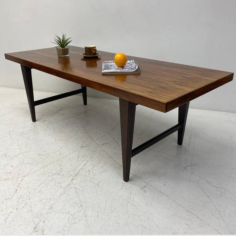 A beautiful Danish midcentury coffee table in solid rosewood. The coffee table top is rectangular & the colour & grain of the rosewood is so beautiful. The legs are midcentury slender tapered design. It is a very elegant designed piece of midcentury