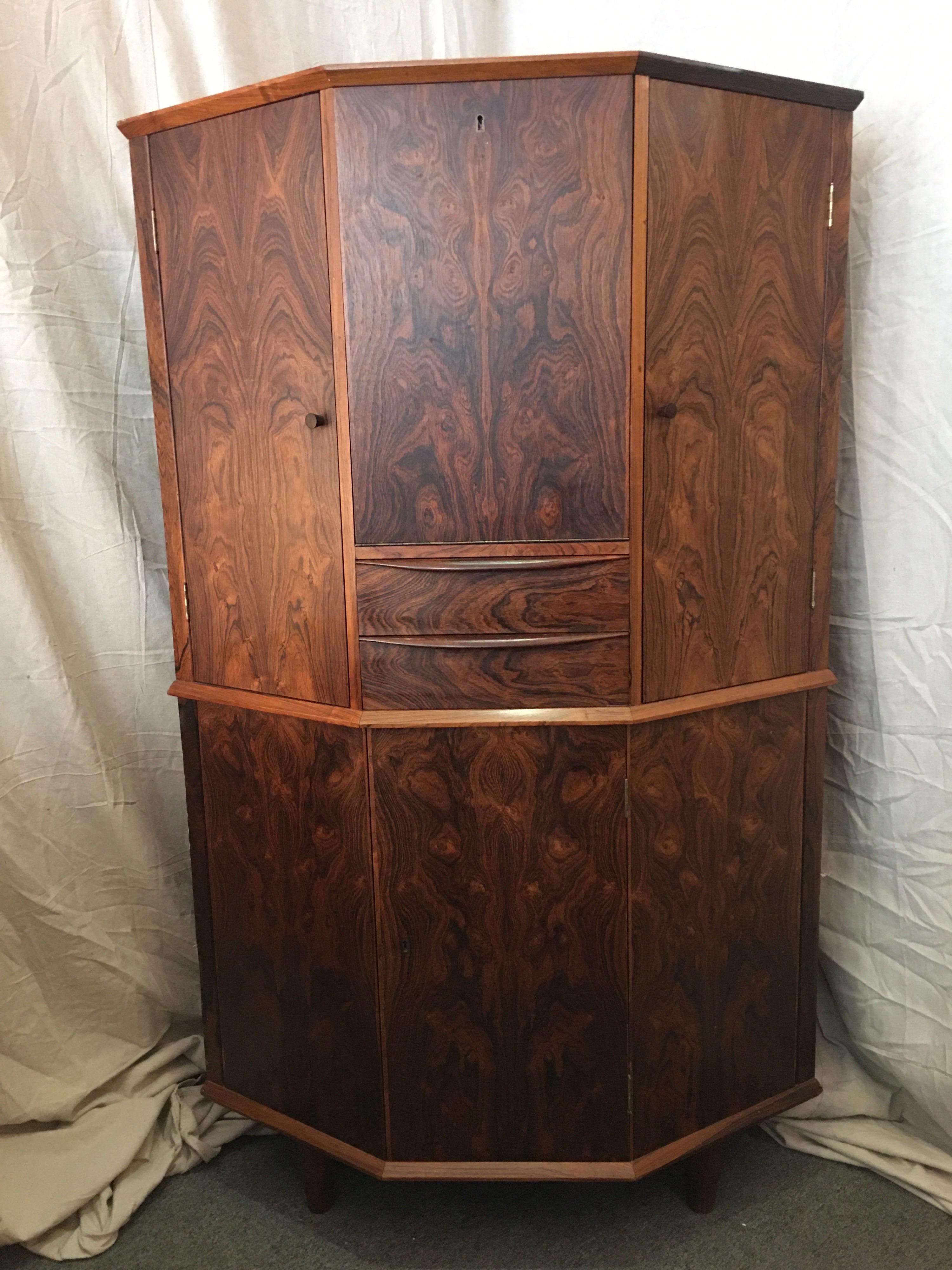 Danish rosewood corner bar cabinet. Fits perfectly into a corner with a folded front design. Top consists of a center Bar Area with doors on each side designed for glassware. Two small pull out drawers below fold down bar. Bottom area consists of a