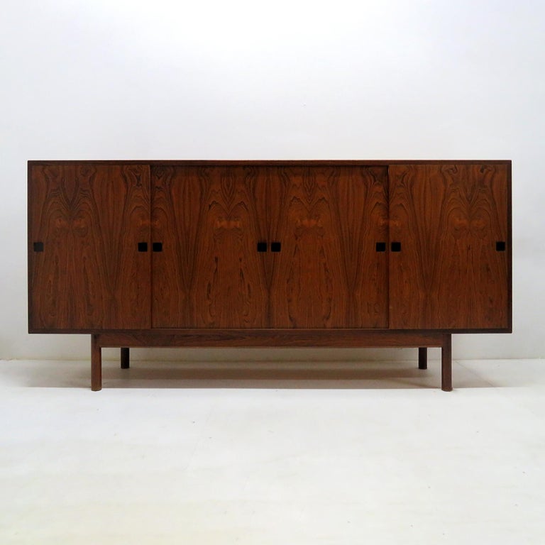 Wonderful tall 1960s Danish rosewood sideboard, with four sliding doors, featuring three shelves in the side compartments and an additional pullout shelf under the middle shelf. The two center compartments feature three open drawers, three shelves