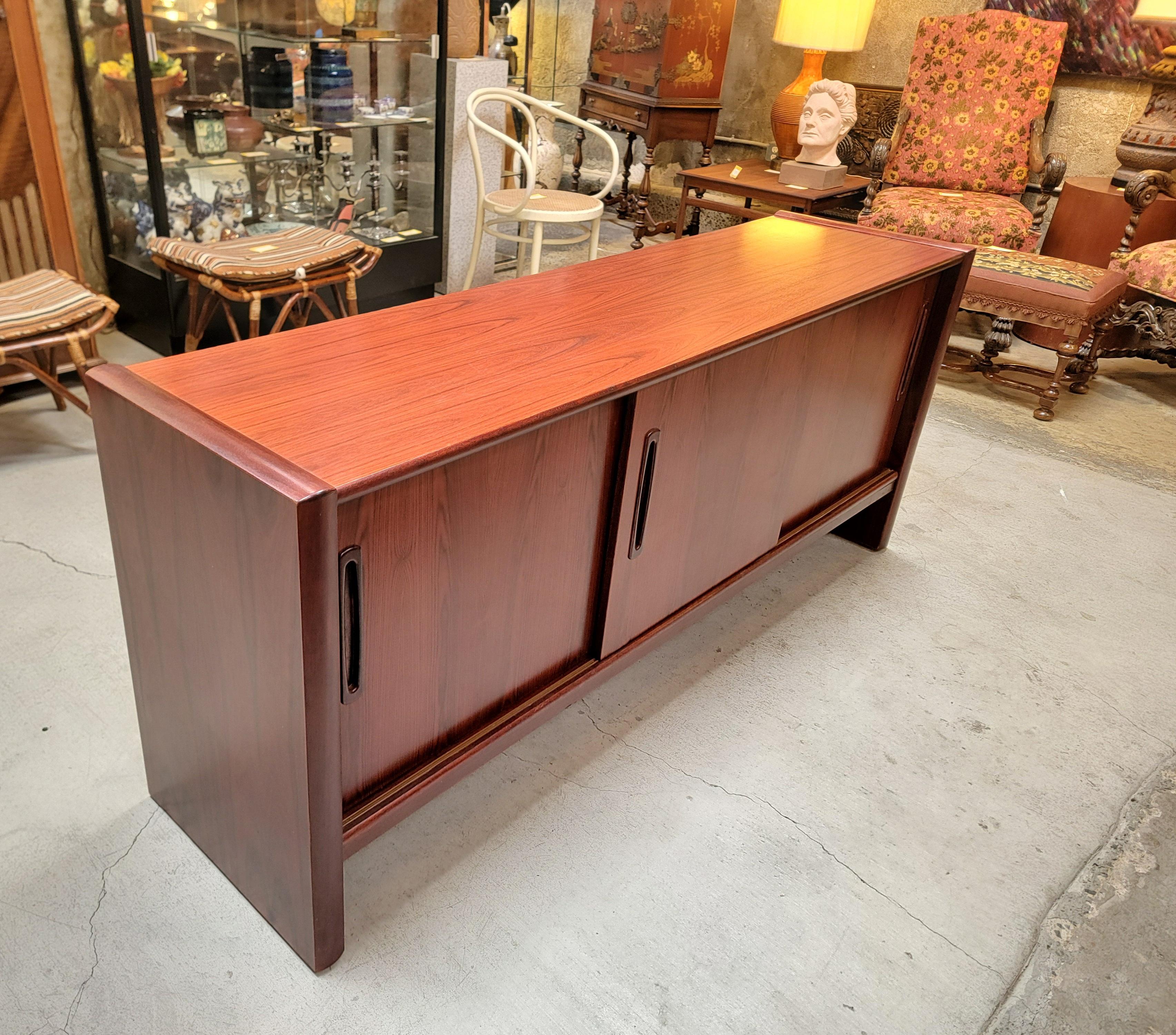 A sliding door rosewood credenza from Denmark. Late 20th century. Beautiful wood grain, in exceptional original condition with very mild wear from use. All doors glide effortlessly. Interior shelving is adjustable. Two interior felt lined flatware