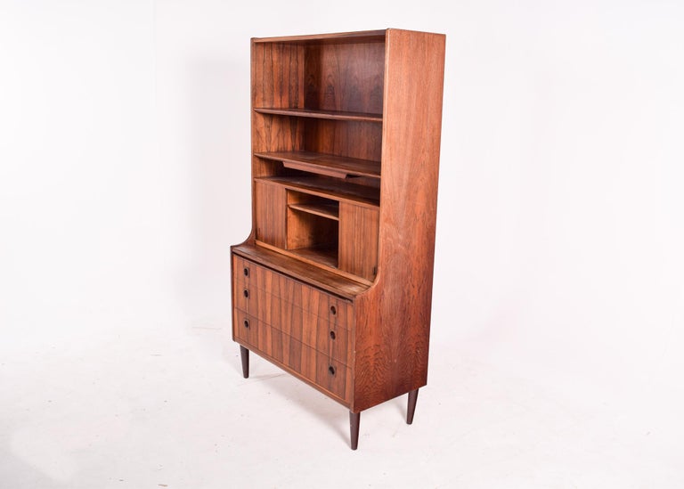 A beautiful Danish rosewood desk cabinet with upper shelving. Features adjustable shelving with additional storage behind the 2 sliding doors and an extendable writing surface. Has a mirror, so you can use this cabinet on your bedroom. Great compact