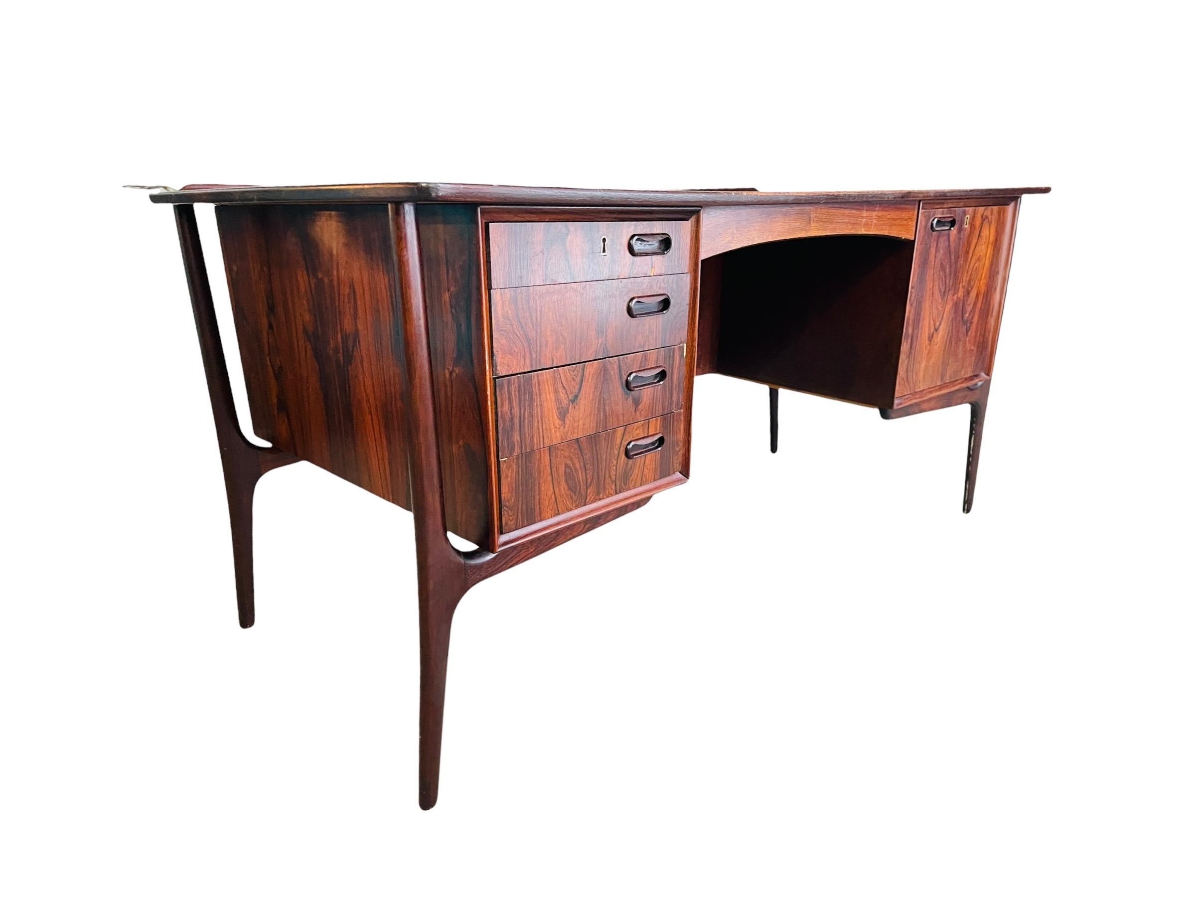 Very stylish, elegant rosewood desk by Svend Aage Madsen for H.P. Hansen made in Denmark circa 1960s. Beautifully grained wood. Organic sculptured frame design with splayed legs enhance a unique character. The desk is fitted with 4 drawers on the