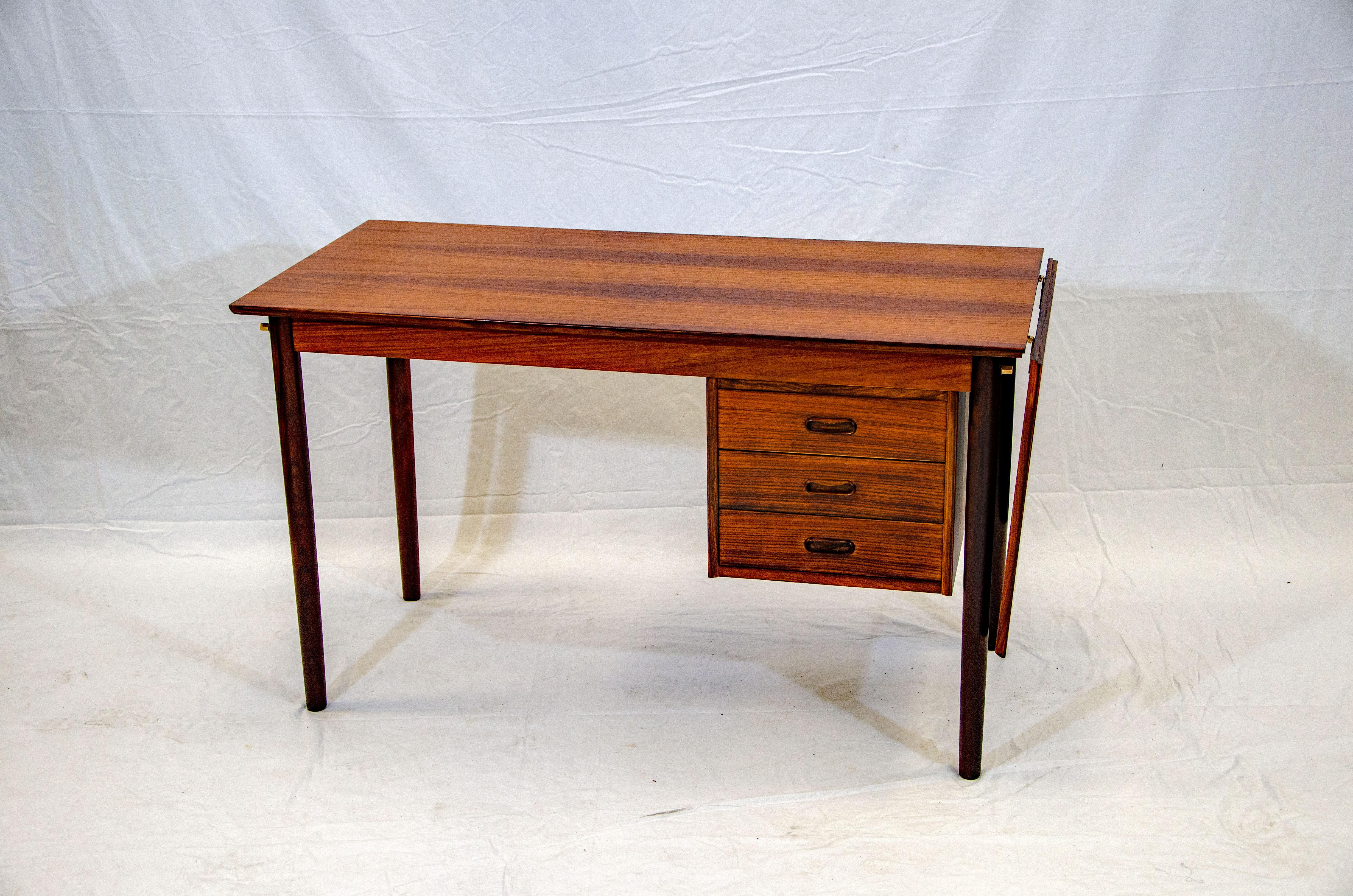 Very nice Danish rosewood desk with book matched grain pattern. The drawer unit can slide from side to side depending on where you want to sit. The hanging extension is 18 1/4