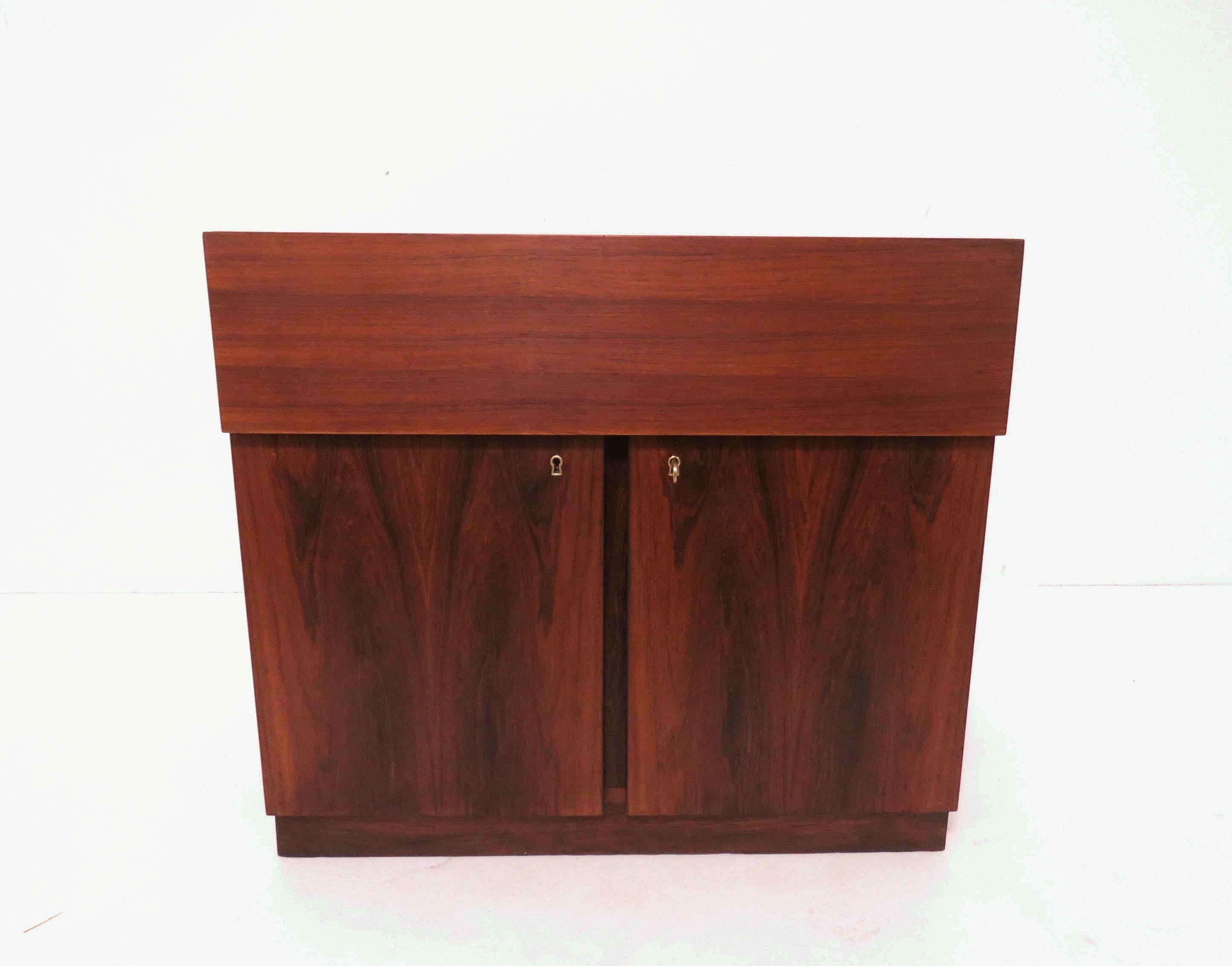 Danish rosewood dry bar cabinet, top opens to reveal laminated surfaces for serving drinks, locked cabinet below. When closed, this measures 31