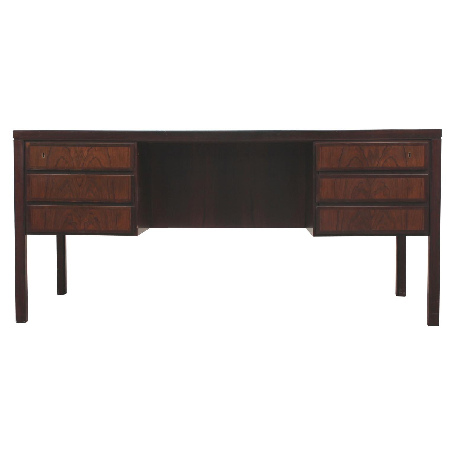 Stunning clean-lined modern Danish rosewood executive desk by Gunni Omann for Omann Jun Møbelfabrik featuring six drawers. The front of the desk features compartments for display as well as a drop down door for additional storage.
