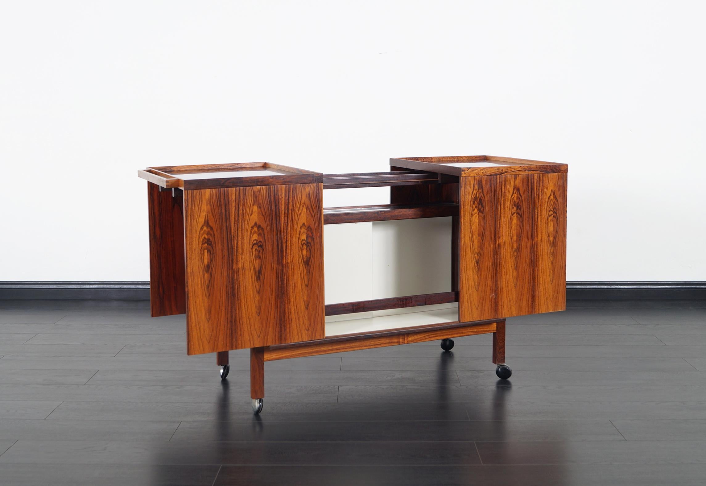 Fabulous Danish rosewood bar cart designed by Niels Erik Glasdam for Vantinge Mobelindustri. Features two sections that slides out to reveal a stylish interior. Inside you will find a glass shelf above bottles storage and white sliding dividers. A