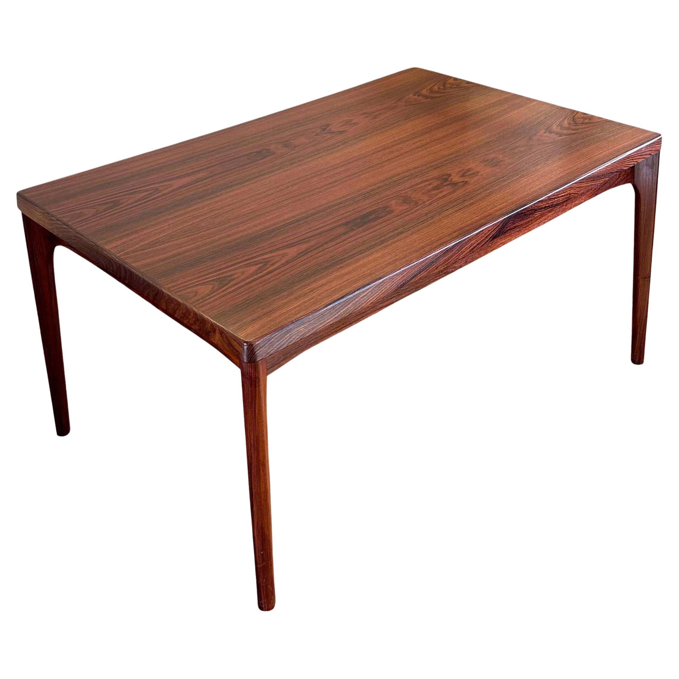 A Scandinavian Modern rosewood dining table with ingeniously hidden extending leaves designed by Henning Kjaernulf for Vejle Stole & Mobelfabrik. Denmark, 1960s. In excellent vintage condition, this is truly the most beautiful edition of this table