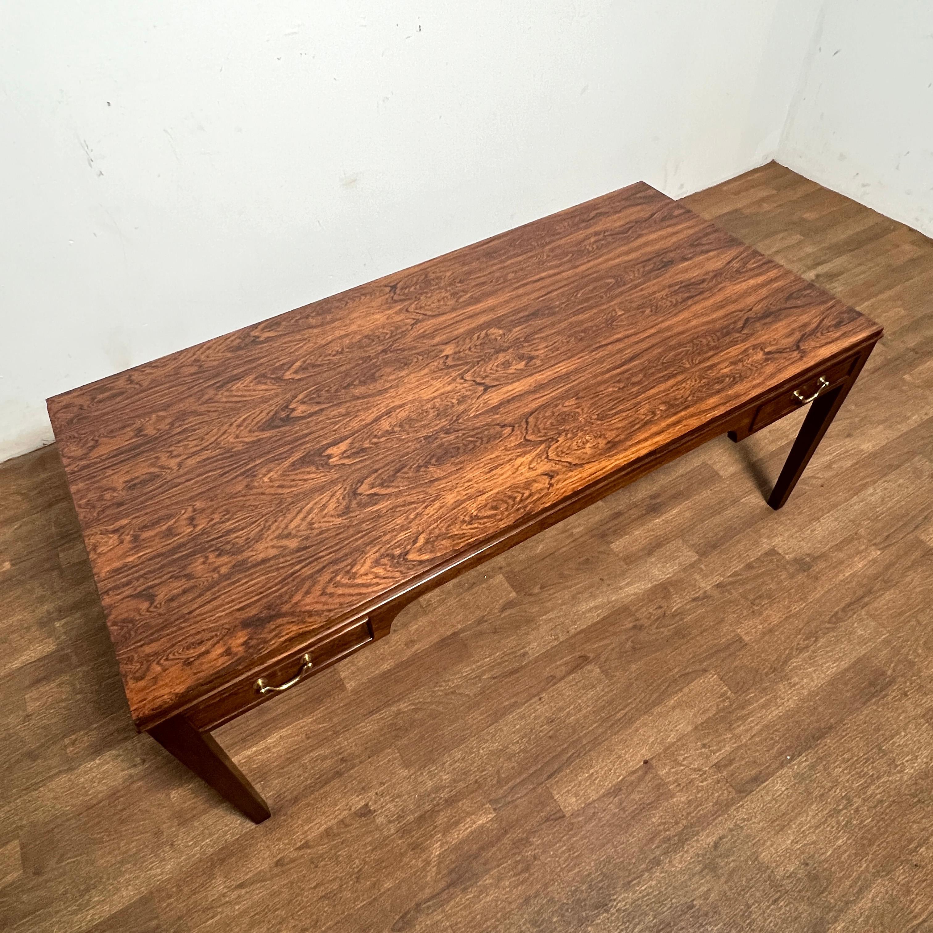 Table basse en bois de rose en forme de bureau avec des tiroirs de rangement flanqués de chaque côté de sa longueur, équipés de poignées en laiton, par Frits Henningsen, Danemark, vers les années 1960.
