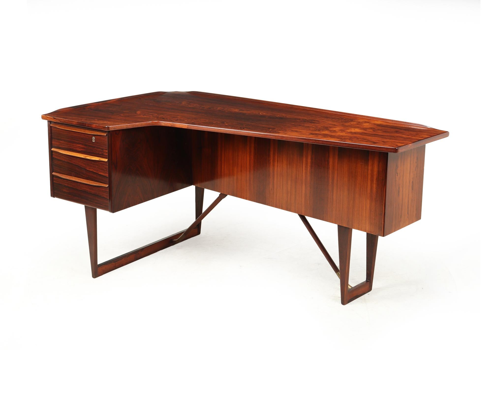 A Mid-Century Modern boomerang desk. Design by Peter Løvig Nielsen for Hedensted Møbelfabrik. Specialist Danish design from the mid fifties. The desk was produced in Denmark from solid rosewood and rosewood veneer with a nice warm grain. This