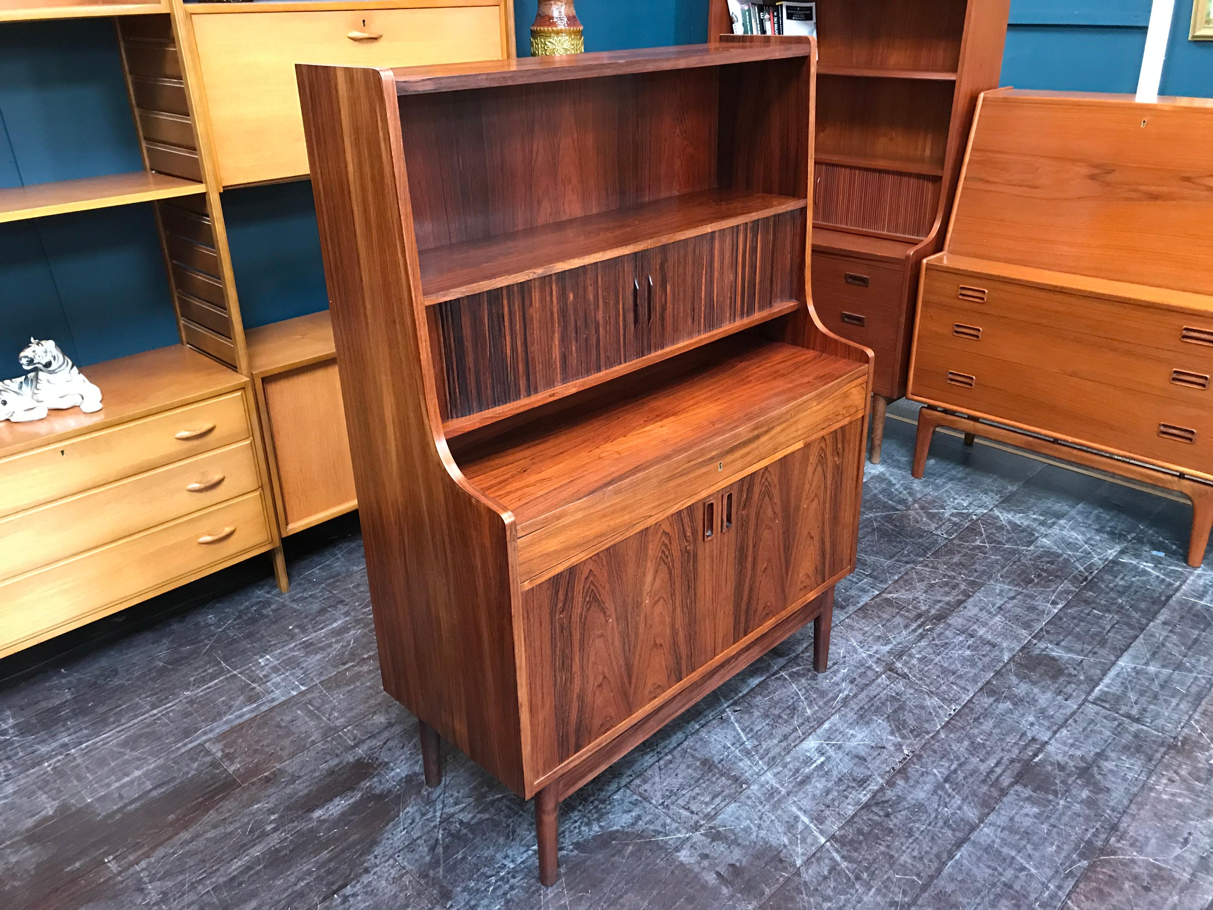 This stunning rosewood desk is an elegant offering from one of Denmark’s finest furniture makers. This high secretaire was designed in the 1960s, probably by Johannes Sorth. It features a shelved cupboard space, a pull-out desktop above the