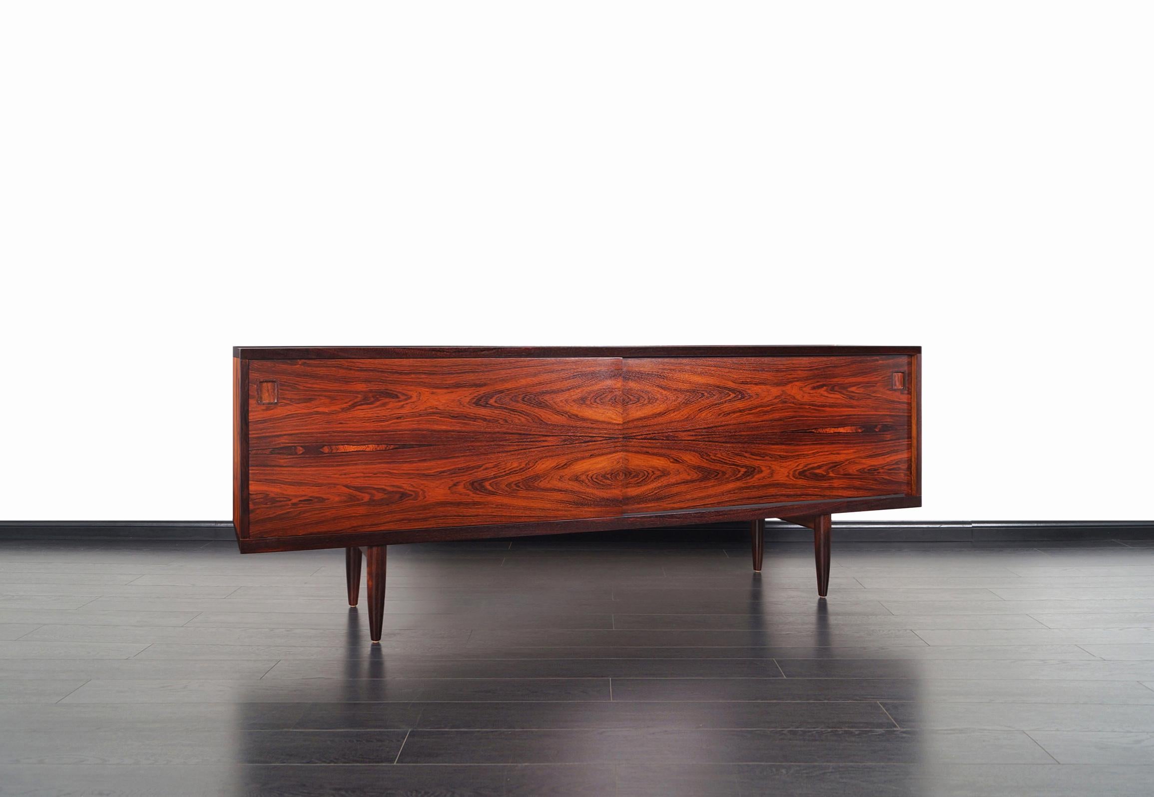 This rare Danish Brazilian rosewood credenza was designed by Niels O. Møller and produced by J.L. Møller Møbelfabrik, model # 20. Sitting on solid rosewood tapered legs, the casing features two sliding door panels with exotic Brazilian rosewood
