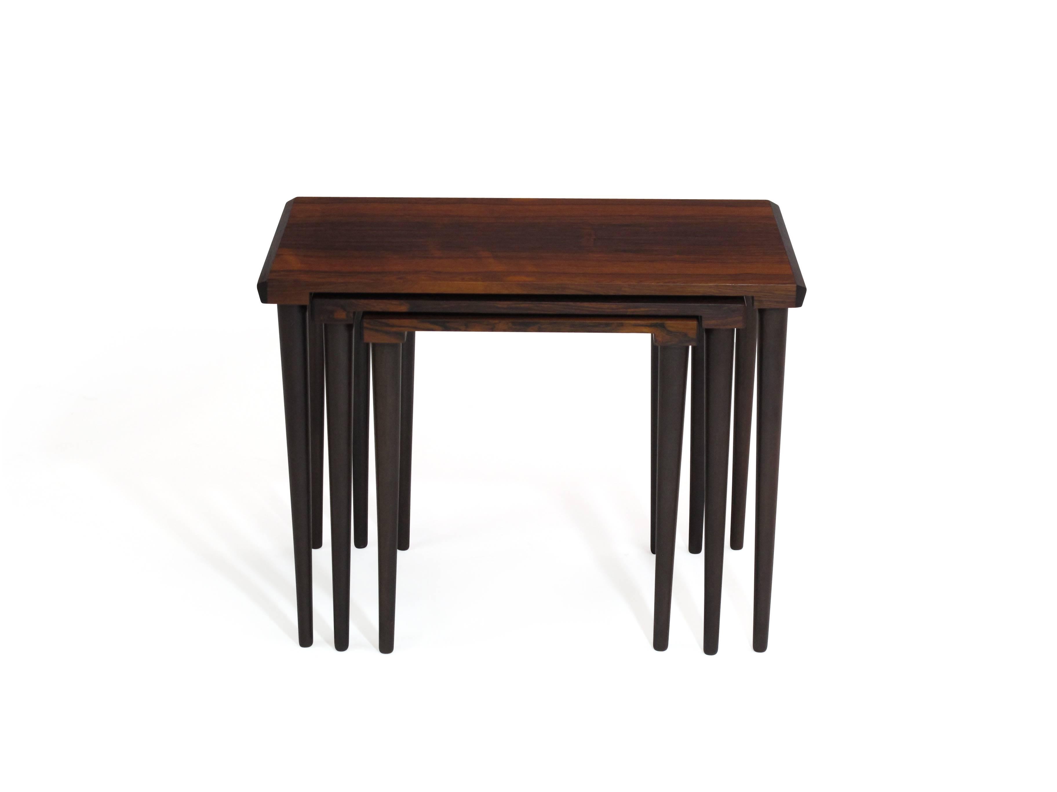 Set of three Danish nesting tables crafted of vibrant rosewood with bevelled edges, and raised on tapered legs. The set of three tables have been finely restored and are in excellent condition.