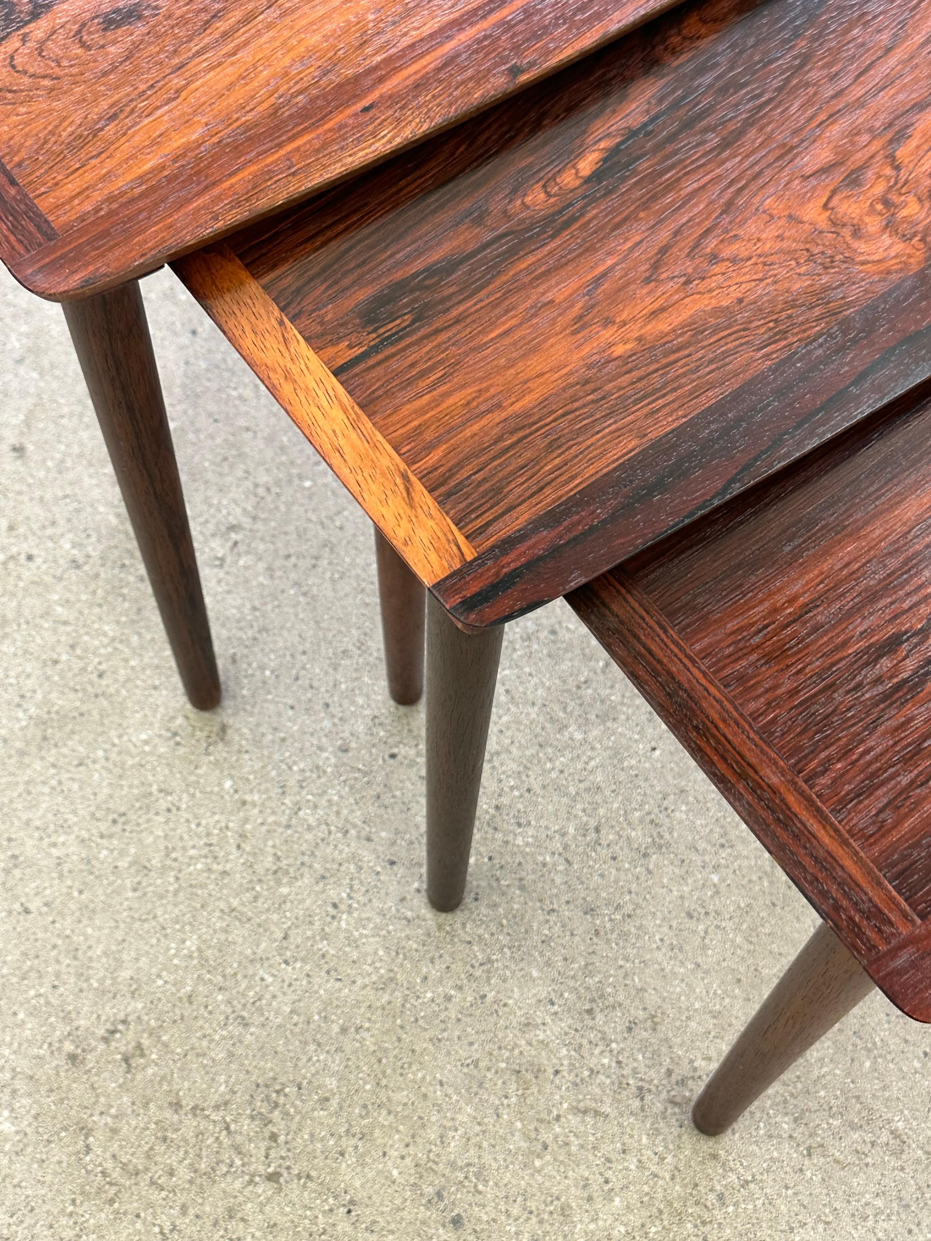 Danish rosewood nesting tables by Mobelintarsia . These tables feature slender tapered legs and curvilinear tops with nicely beveled edges and a rich grain pattern. 