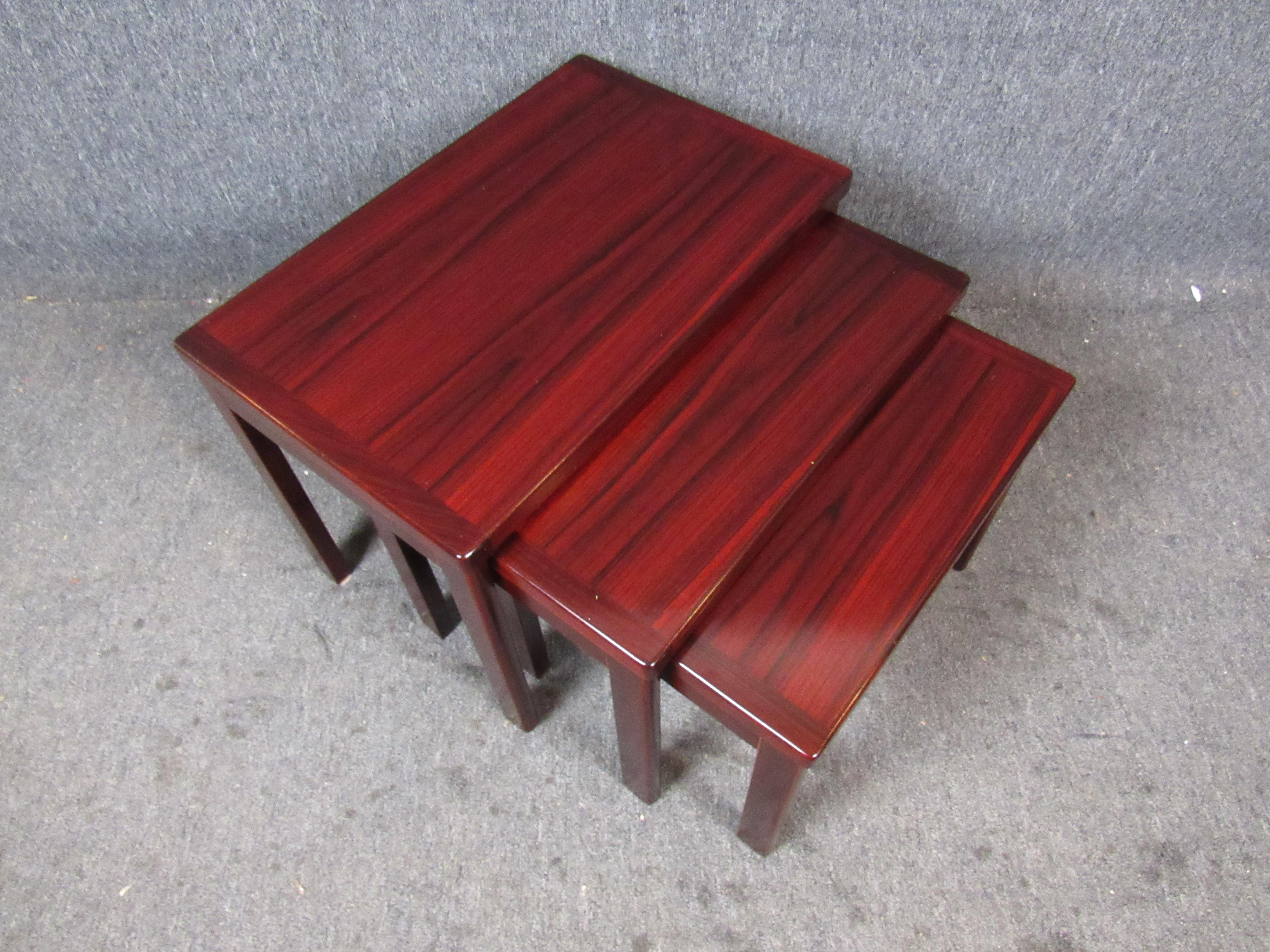 Absolutely stunning set of three rosewood nesting tables by V.S.M. Denmark. Each table proudly displays the beautiful deep, red grains that make this wood so desirable. Authentic Danish craftsmanship ensures sturdiness for years to come. Large table
