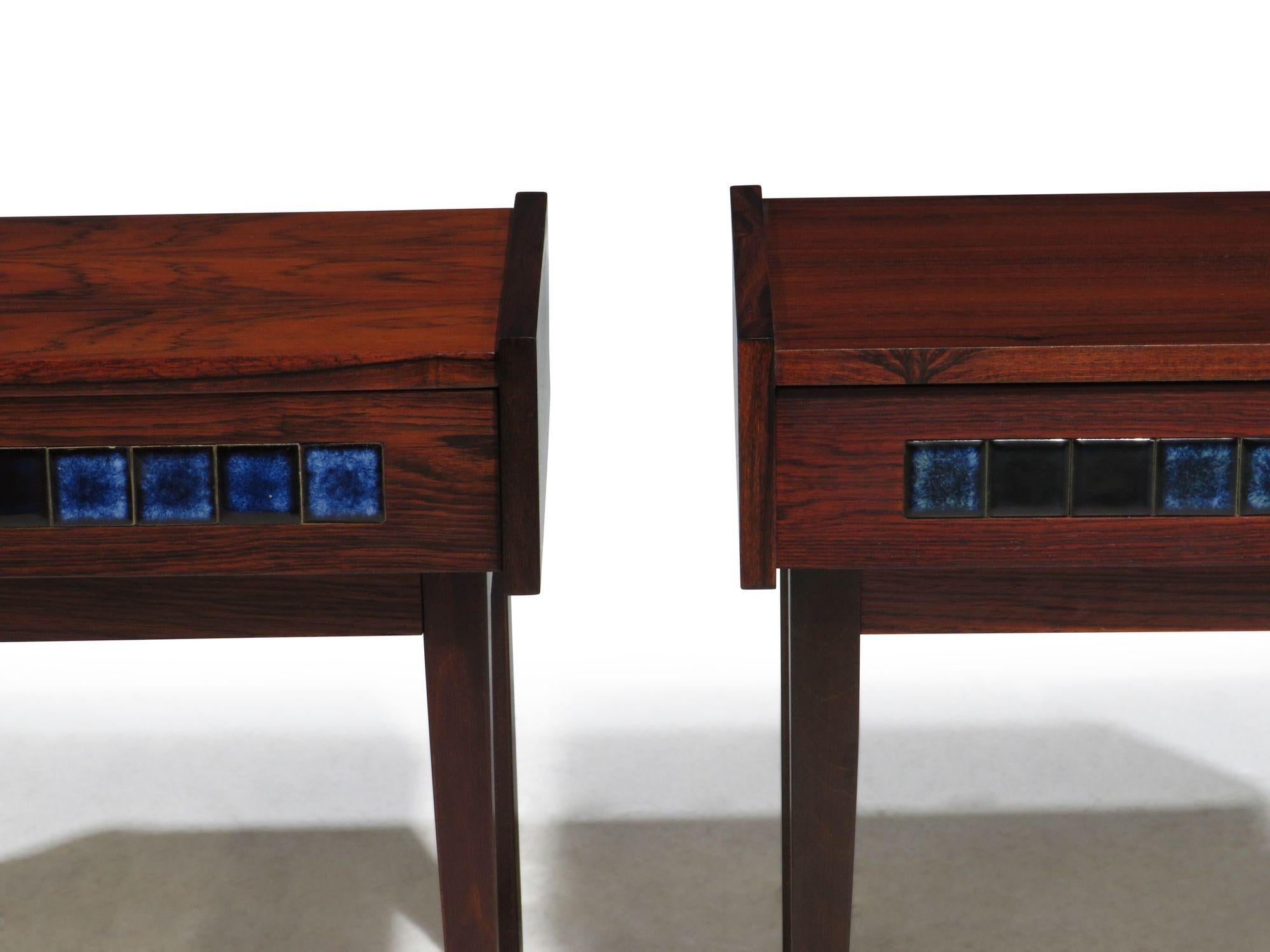 Pair of Scandinavian nightstands made in Denmark, circa 1965. The nightstands are crafted of Brazilian Rosewood and feature one drawers with blue ceramic tile details. Raised on tapered legs. Nightstands are fully restored in excellent condition