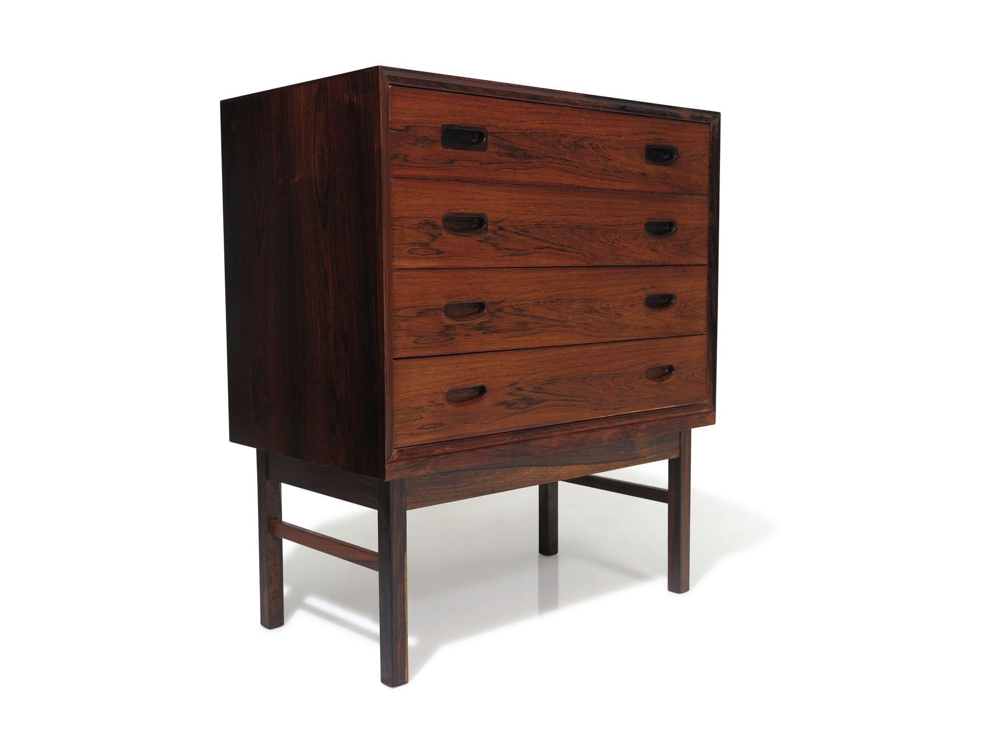 High-quality Danish chest of drawers attributed to Kofoed Larsen, crafted of Brazilian rosewood with four book-matched drawers featuring recessed handles, raised on solid rosewood legs. Minimalist design with charming details, this flexible piece