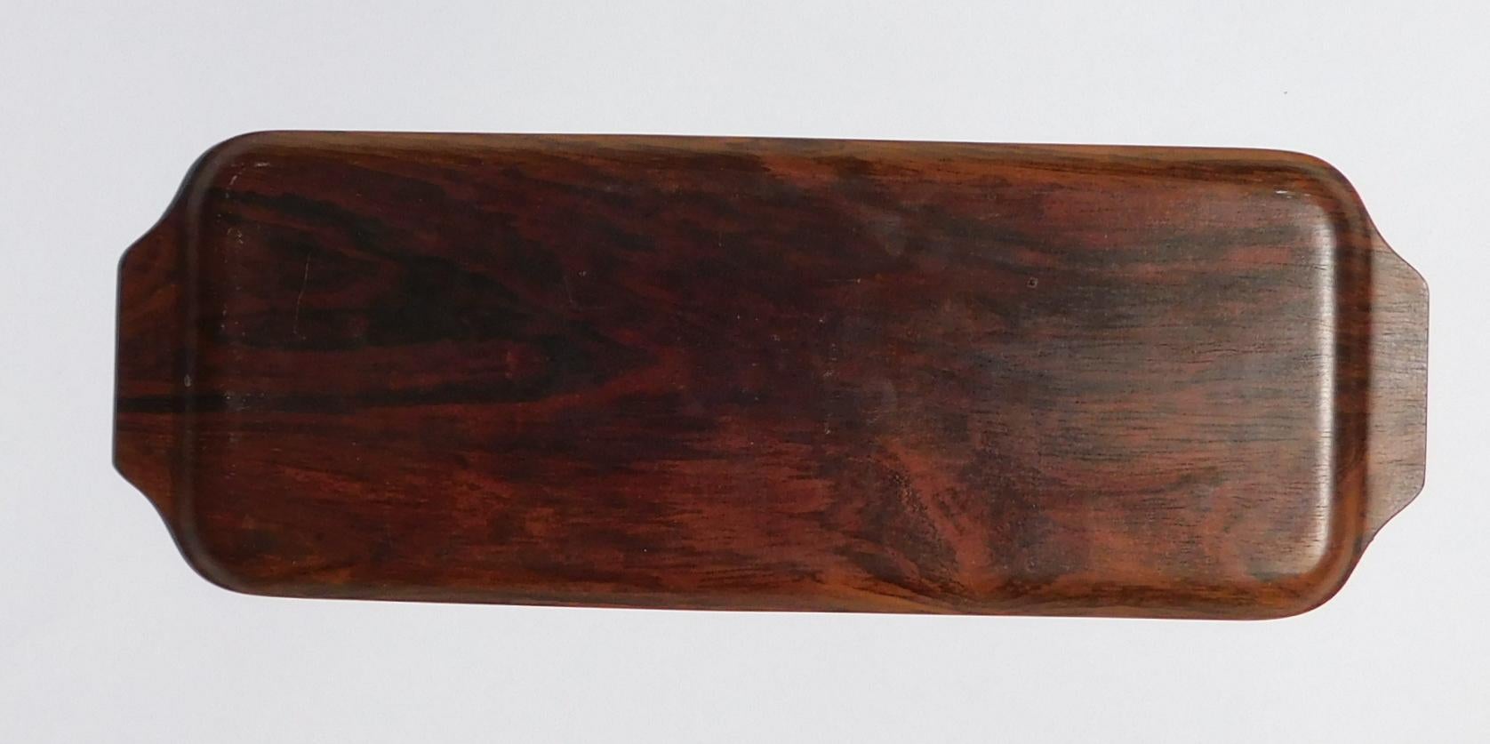 Ce plateau en bois de rose danois est une pièce étonnante du modernisme du milieu du siècle qui ne manquera pas d'impressionner tout collectionneur d'antiquités. 
Le plateau est estampillé sur la base 