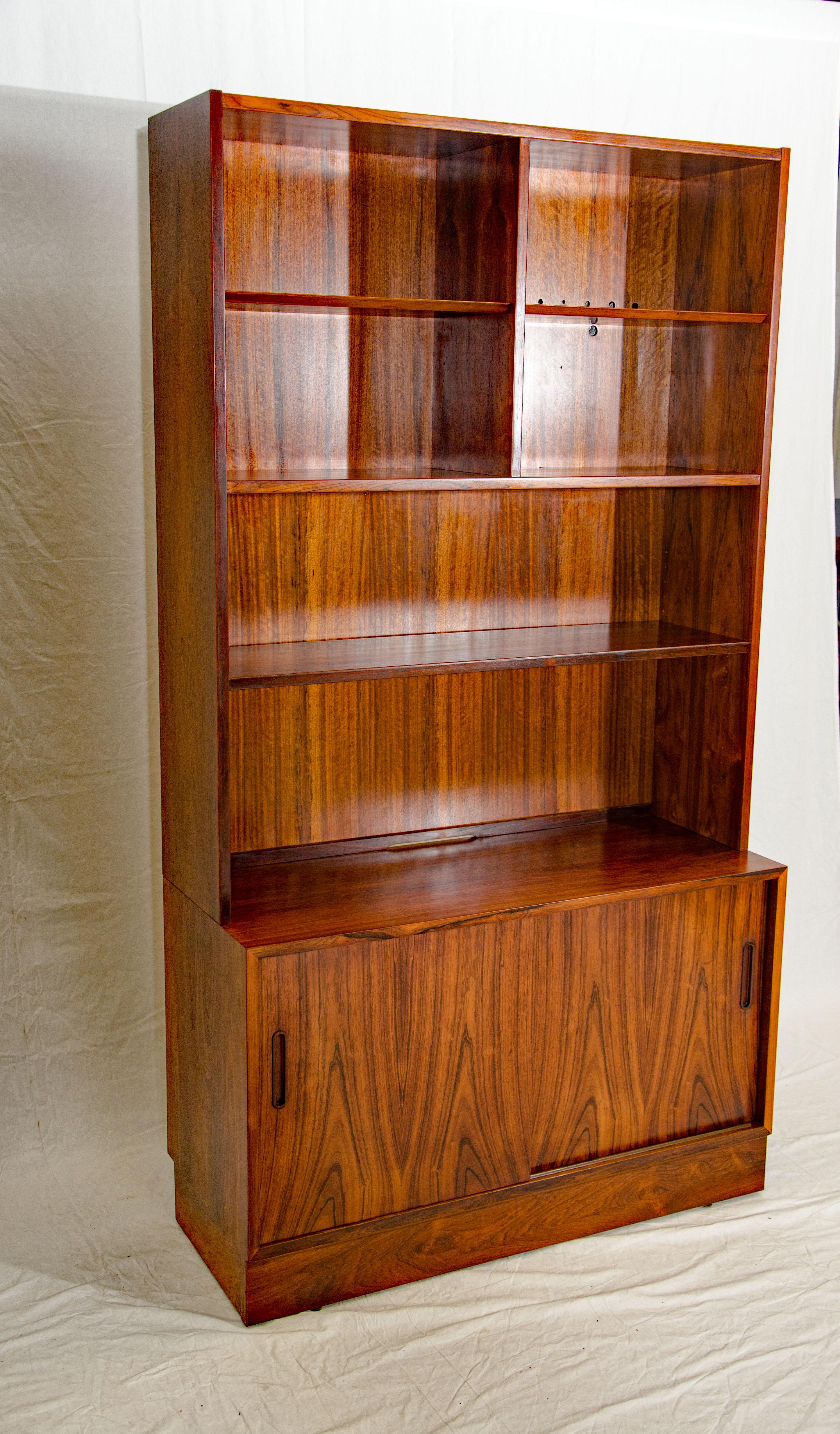 Nice medium size Danish rosewood bookcase shelf section on top of a cabinet with two sliding doors. The lower cabinet has small drawers on one side and an adjustable shelf on the other. The interior of the lower cabinet is birch. The lower cabinet
